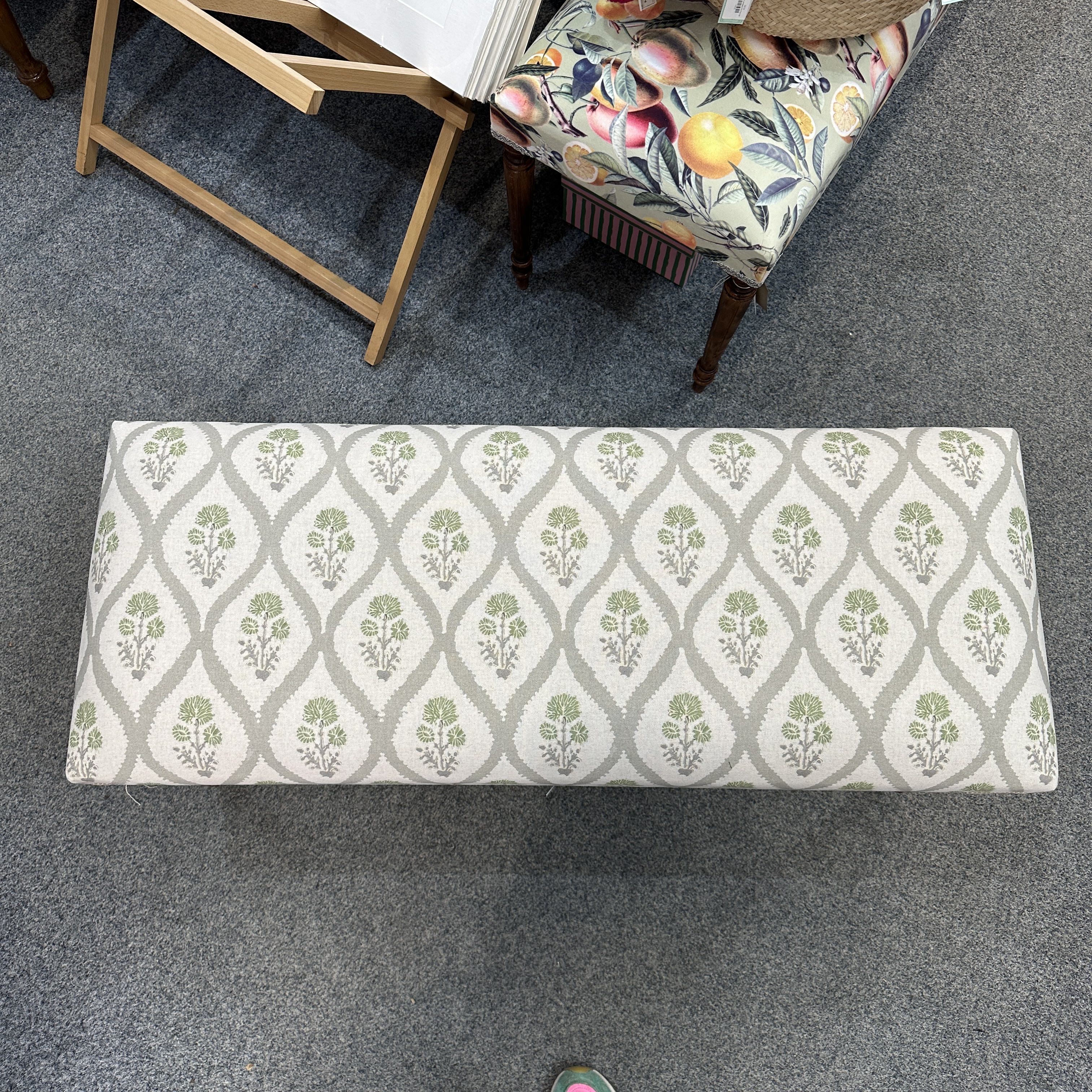 Patterned bench on a carpeted floor with a chair in the background.