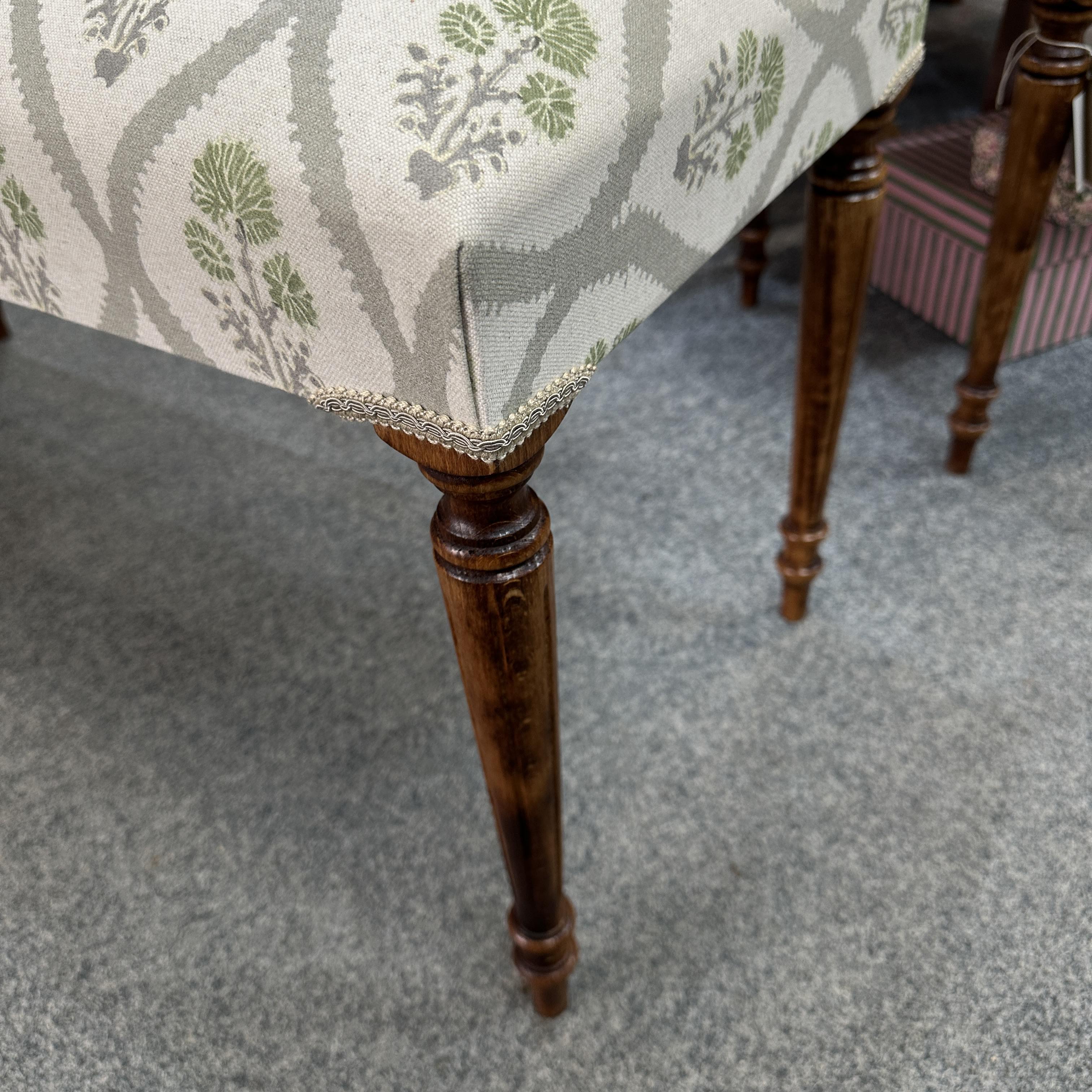 Close-up of a chair leg with floral-patterned fabric on a carpeted floor.