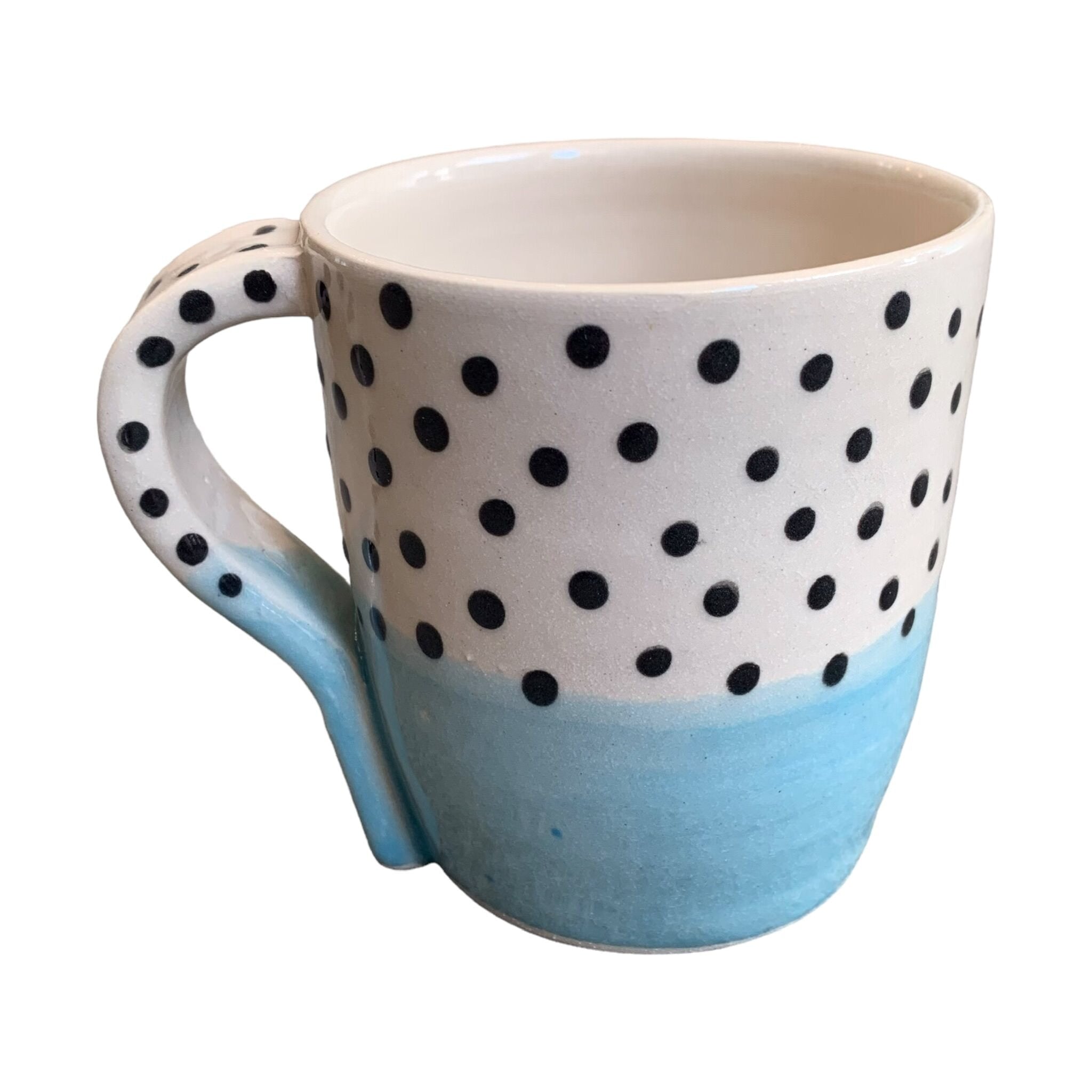 A handmade mug with a pale blue glaze up to the centre and black polka dots on a white background on the top half.