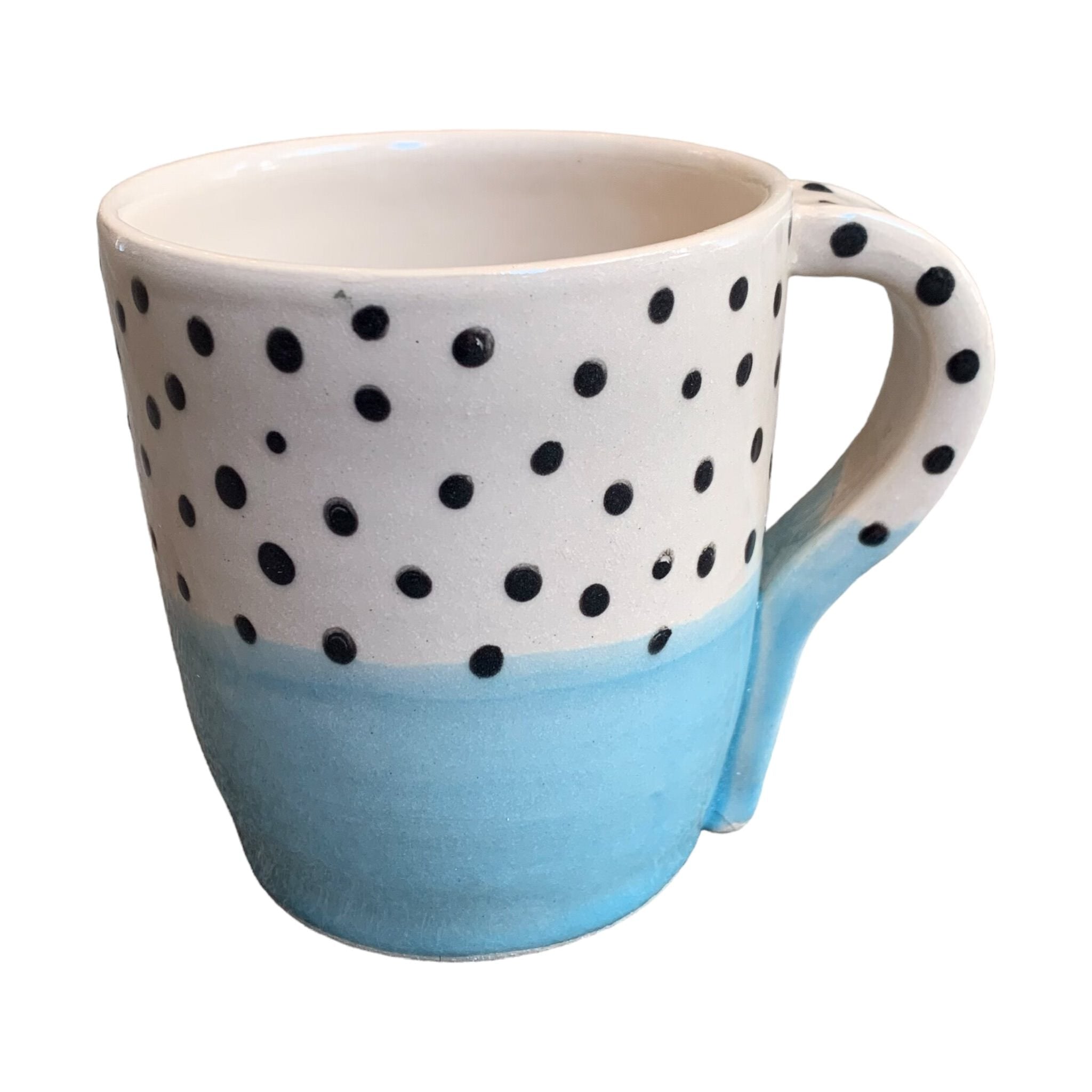 A handmade mug with a pale blue glaze up to the centre and black polka dots on a white background on the top half.
