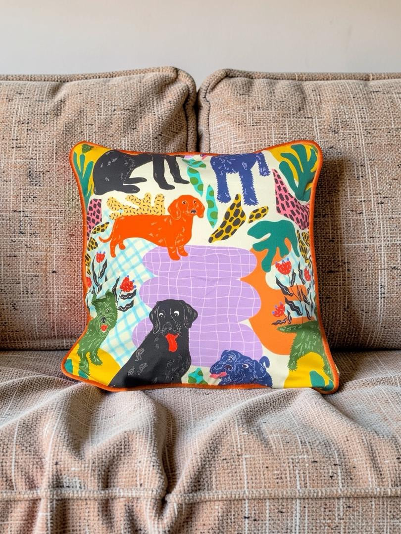 Decorative pillow with colorful dog illustrations on a beige couch.