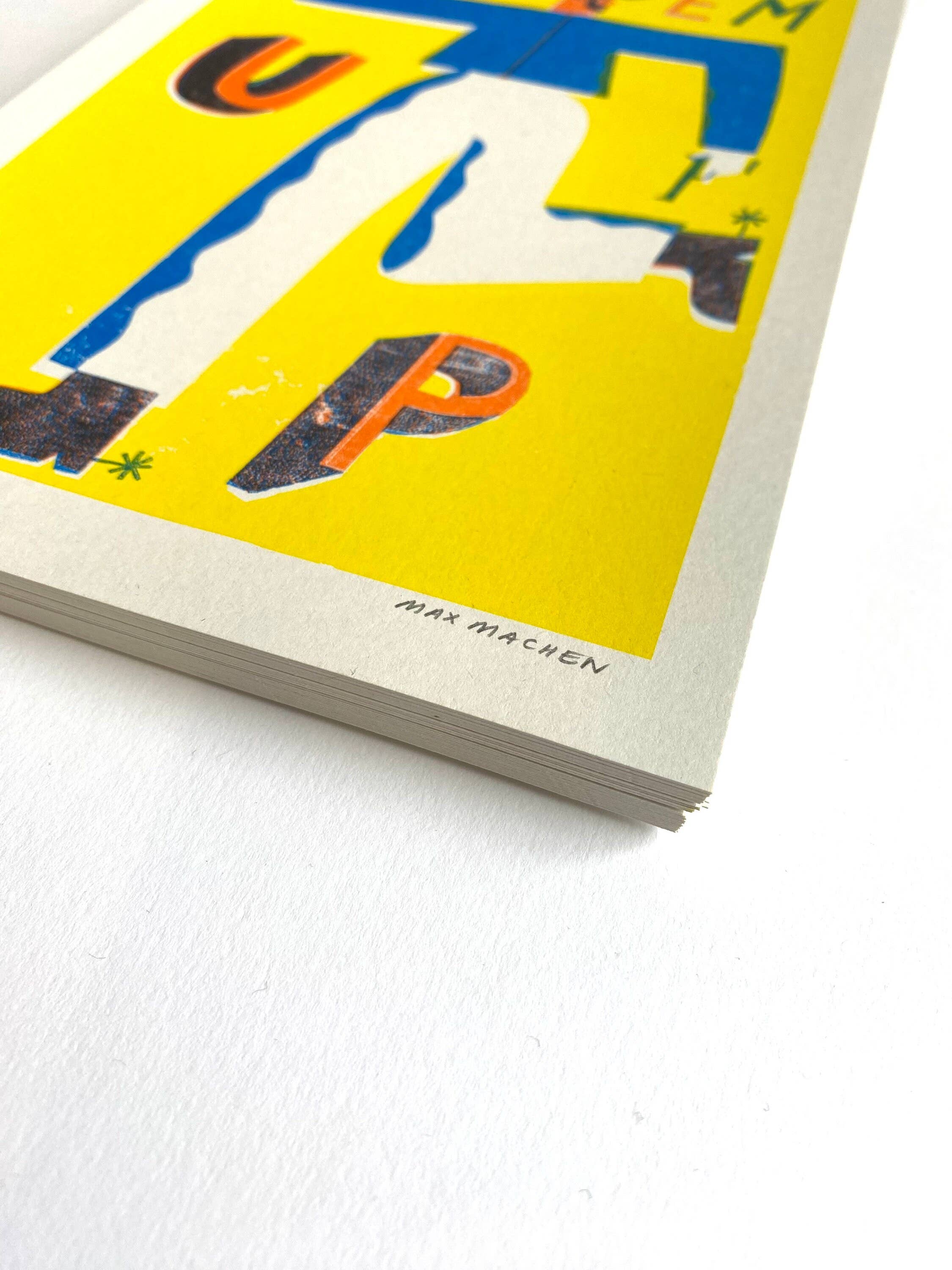 Three-colour risograph print featuring a cowboy wearing a blue shirt and white trousers with the text 'Put Em Up', all against a yellow background.