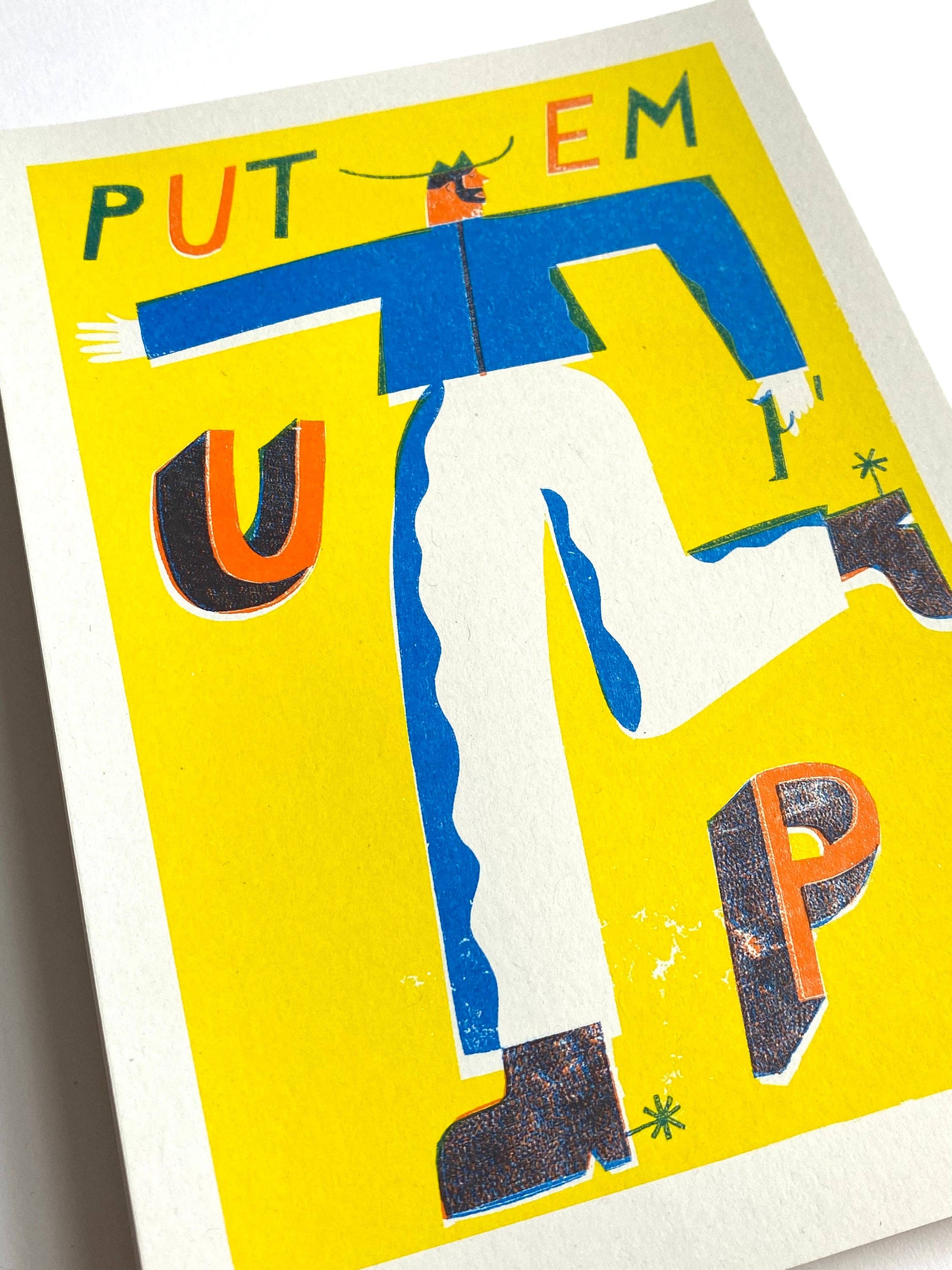 Three-colour risograph print featuring a cowboy wearing a blue shirt and white trousers with the text 'Put Em Up', all against a yellow background.