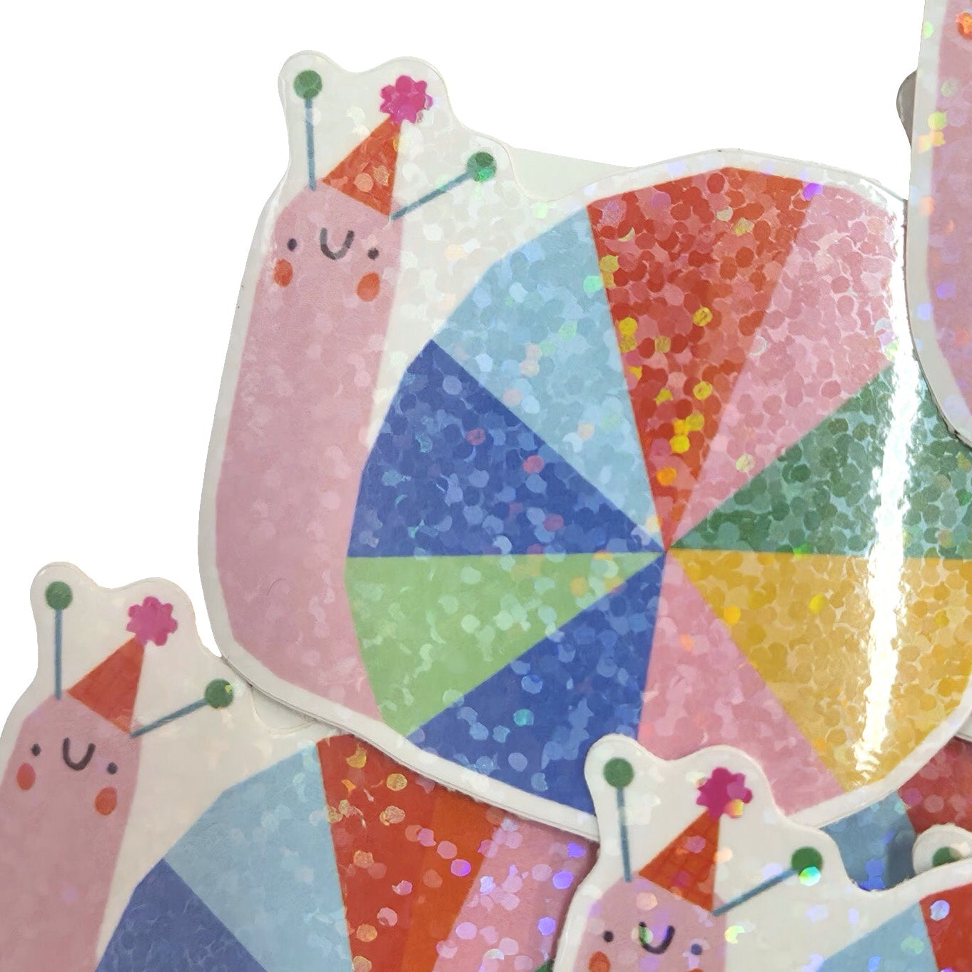 A pile of die-cut stickers featuring cute pink cartoon snails wearing party hats, paired with colorful glittery pinwheel designs on a white background.