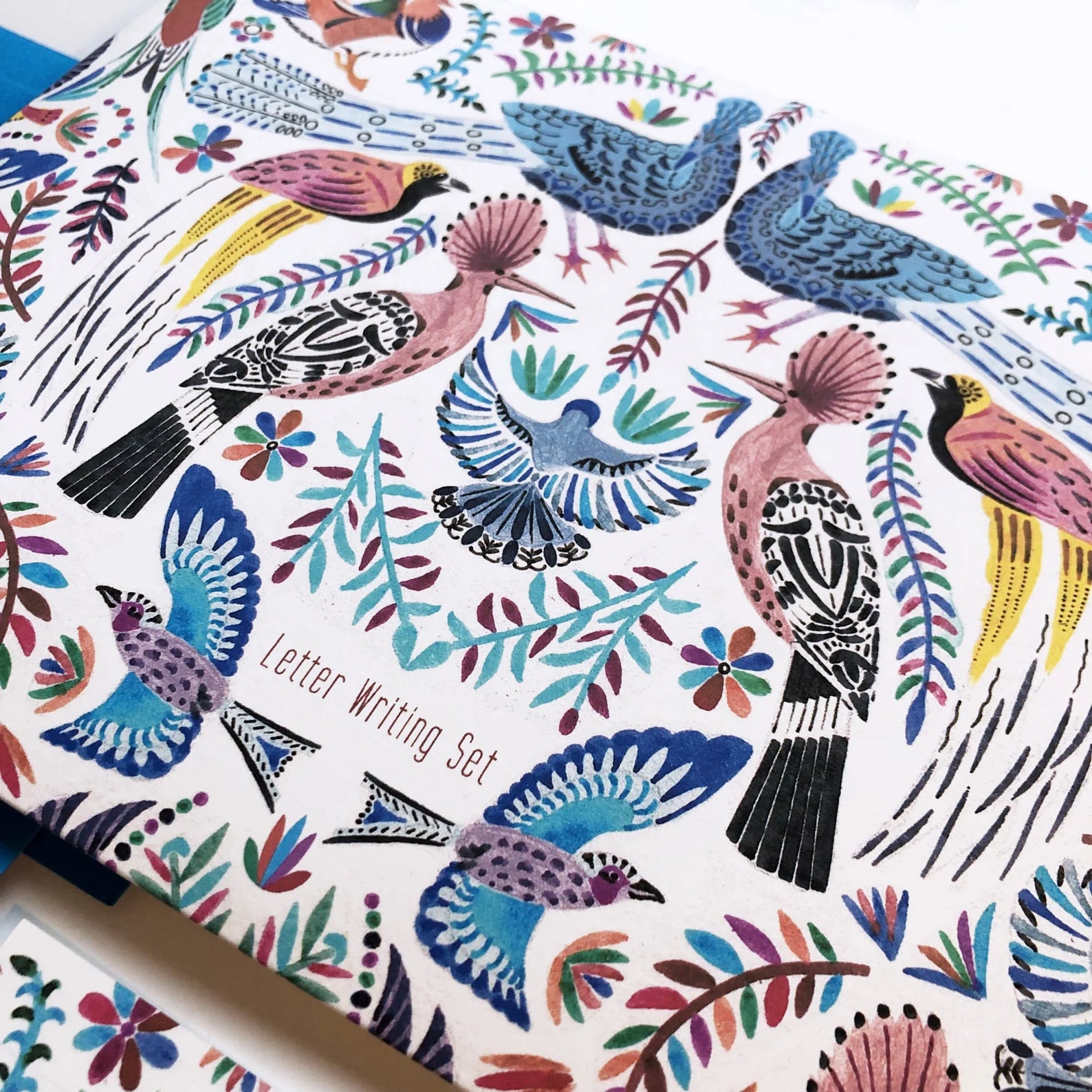 Letter writing set with colorful bird and floral design on a white background.