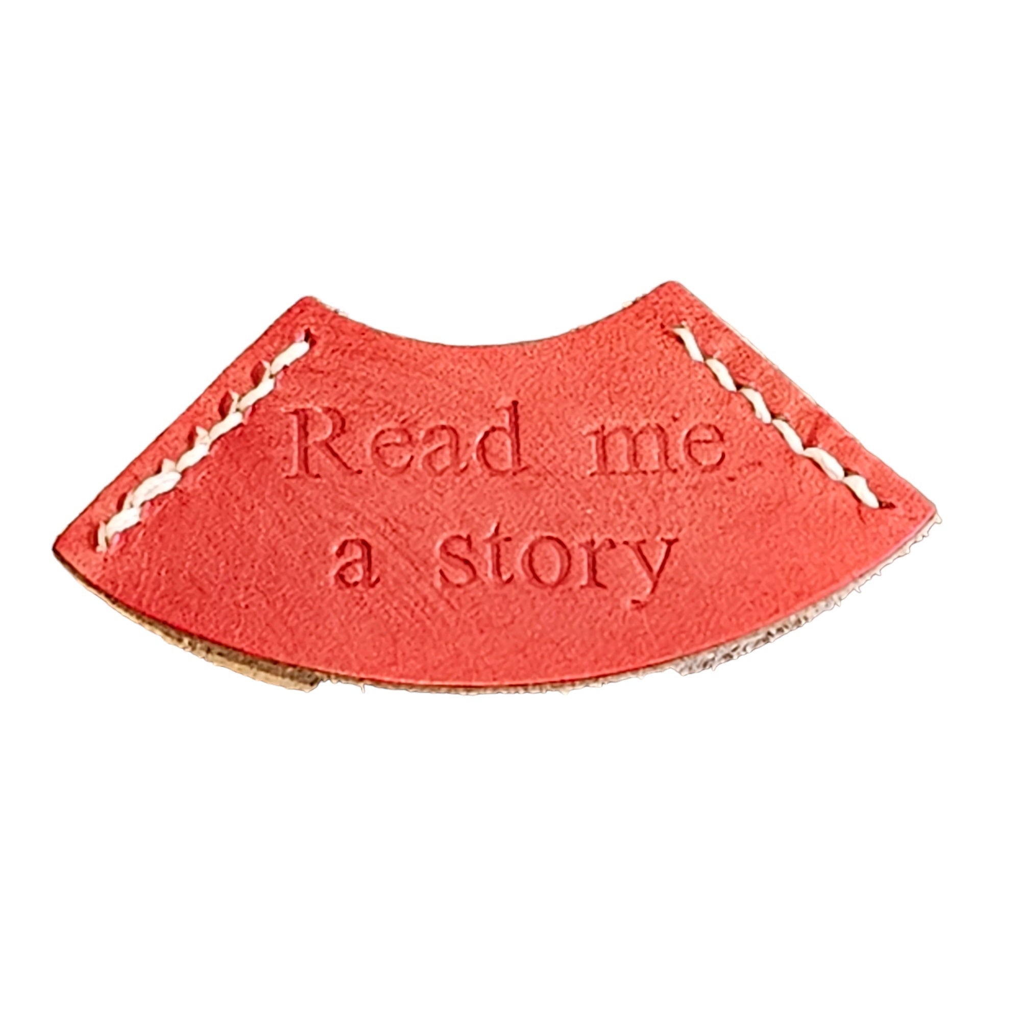 A red leather bookmark with the embossed text 'READ ME A STORY'.