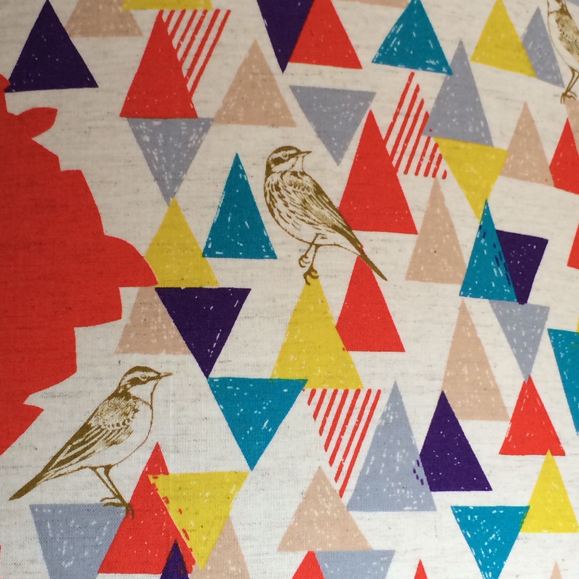 Drum lampshade covered in Echino cotton featuring a red background with panels of multicolured triangles and light brown birds.