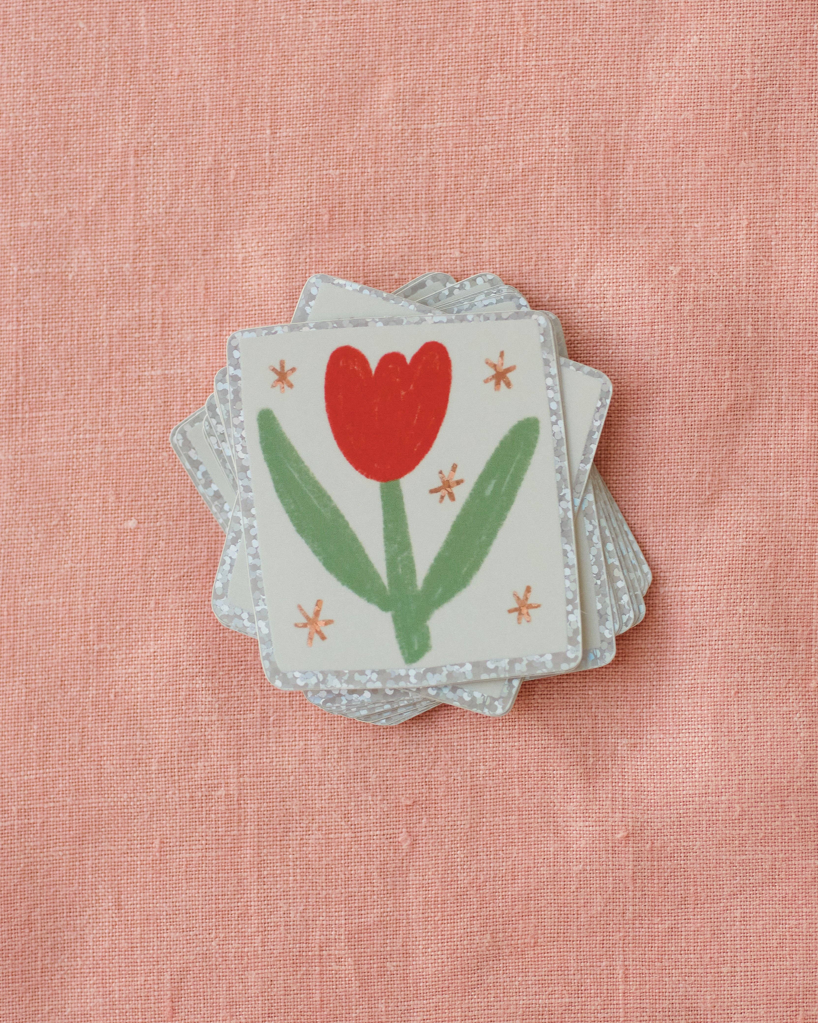 Stack of stickers with a red tulip design on a pink textured background.