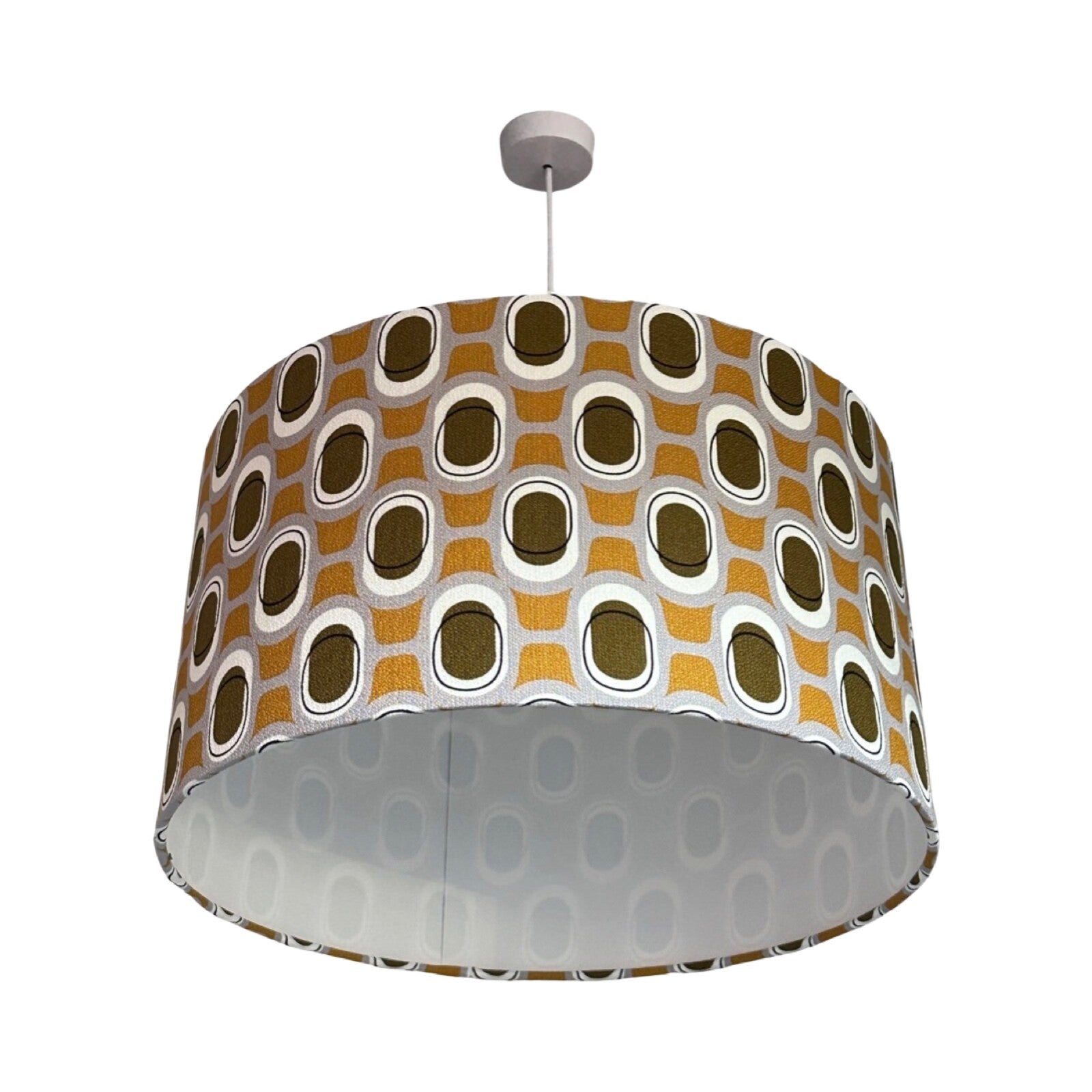 Drum lampshade covered in barkcloth fabric with a mid-century inspired pattern in mustard and brown.