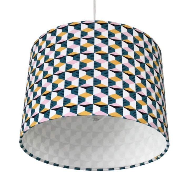 Close up of a drum lampshade covered in retro-style cotton fabric with a mustard, pink, white and blue geometric pattern.