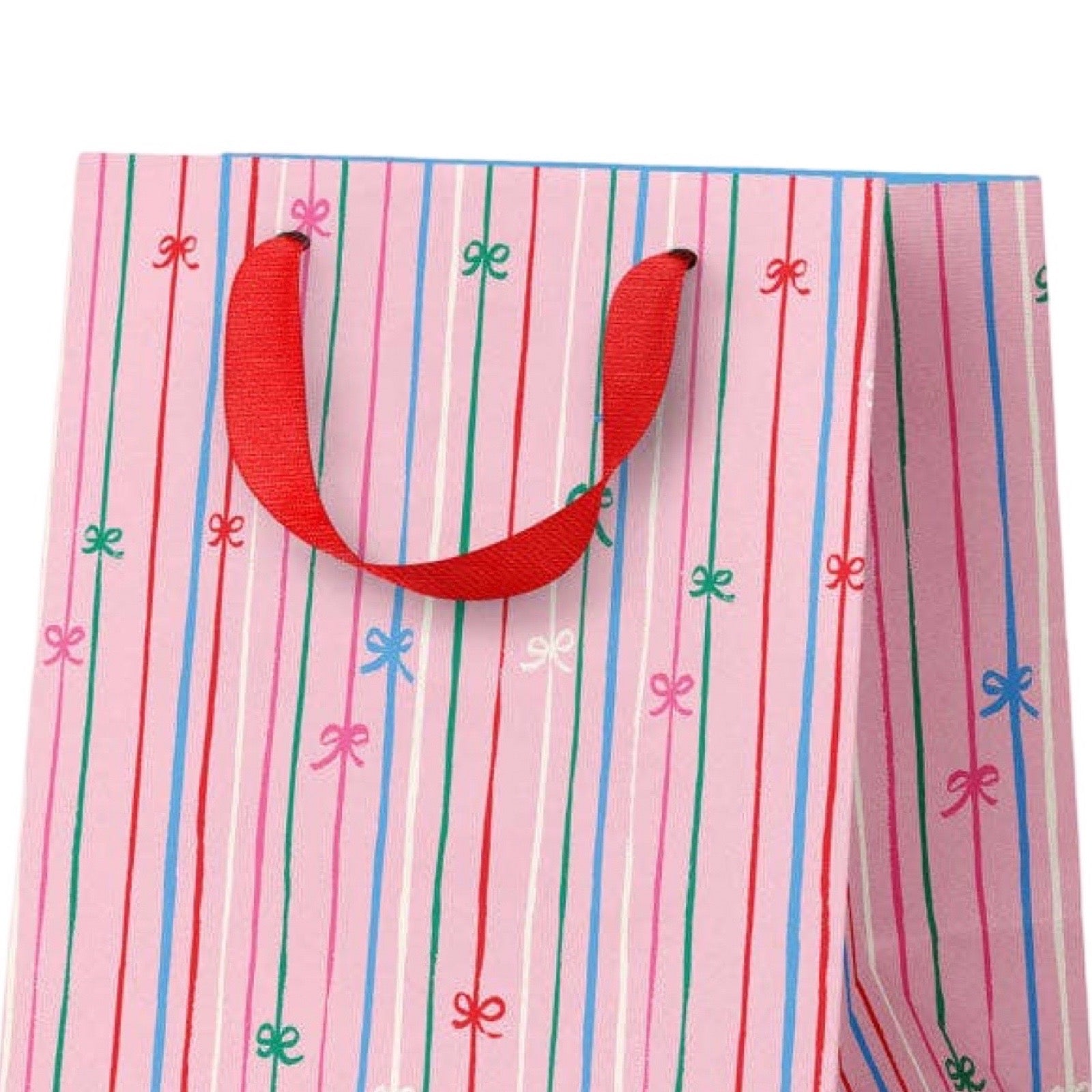 A pink gift bag with vertical red, green, and blue stripes, decorated with small bow motifs in pink, blue, and green, featuring red ribbon handles.