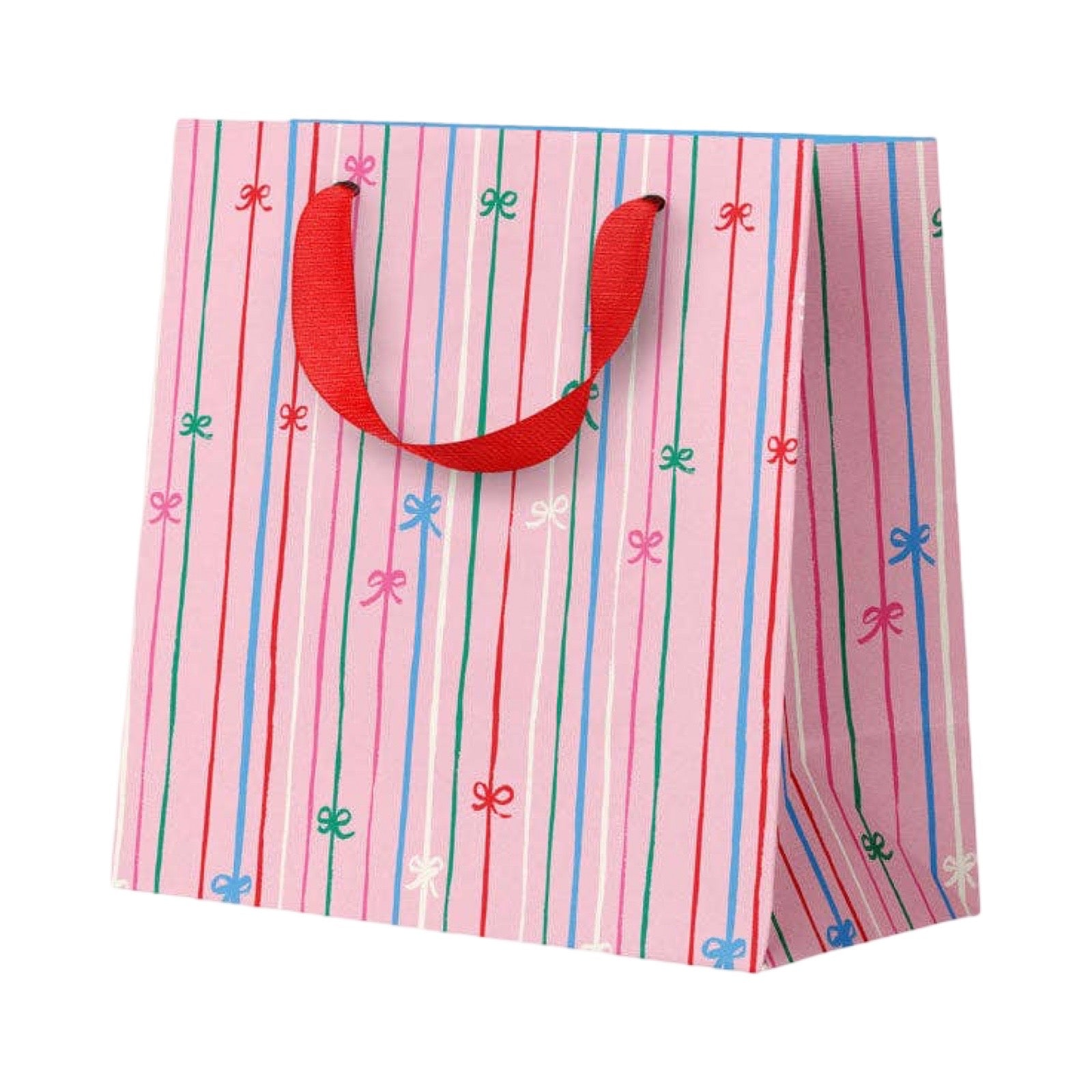 A pink gift bag with vertical red, blue, and green stripes and small bow motifs, with red ribbon handles, on a plain white background.
