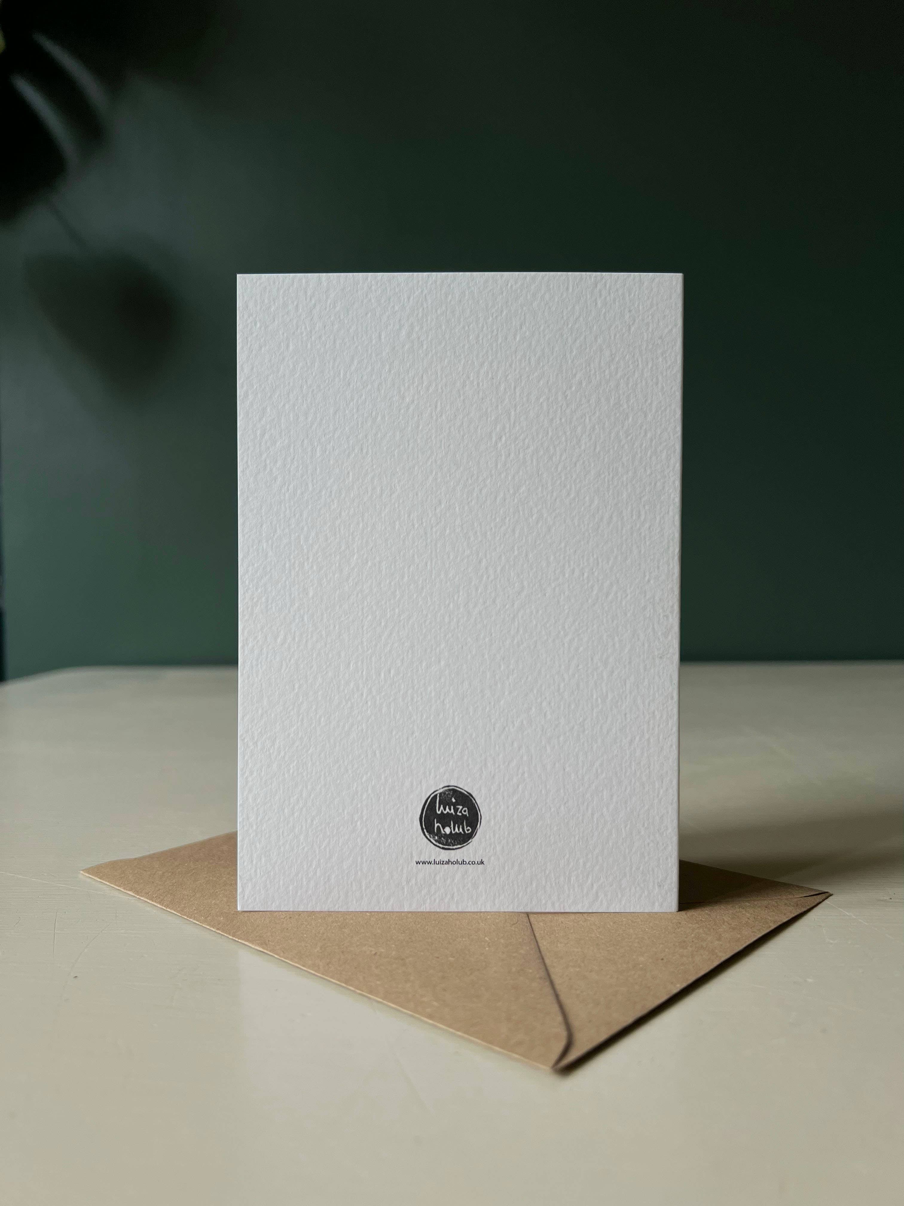 White greeting card with a black logo on a brown envelope against a dark green background.
