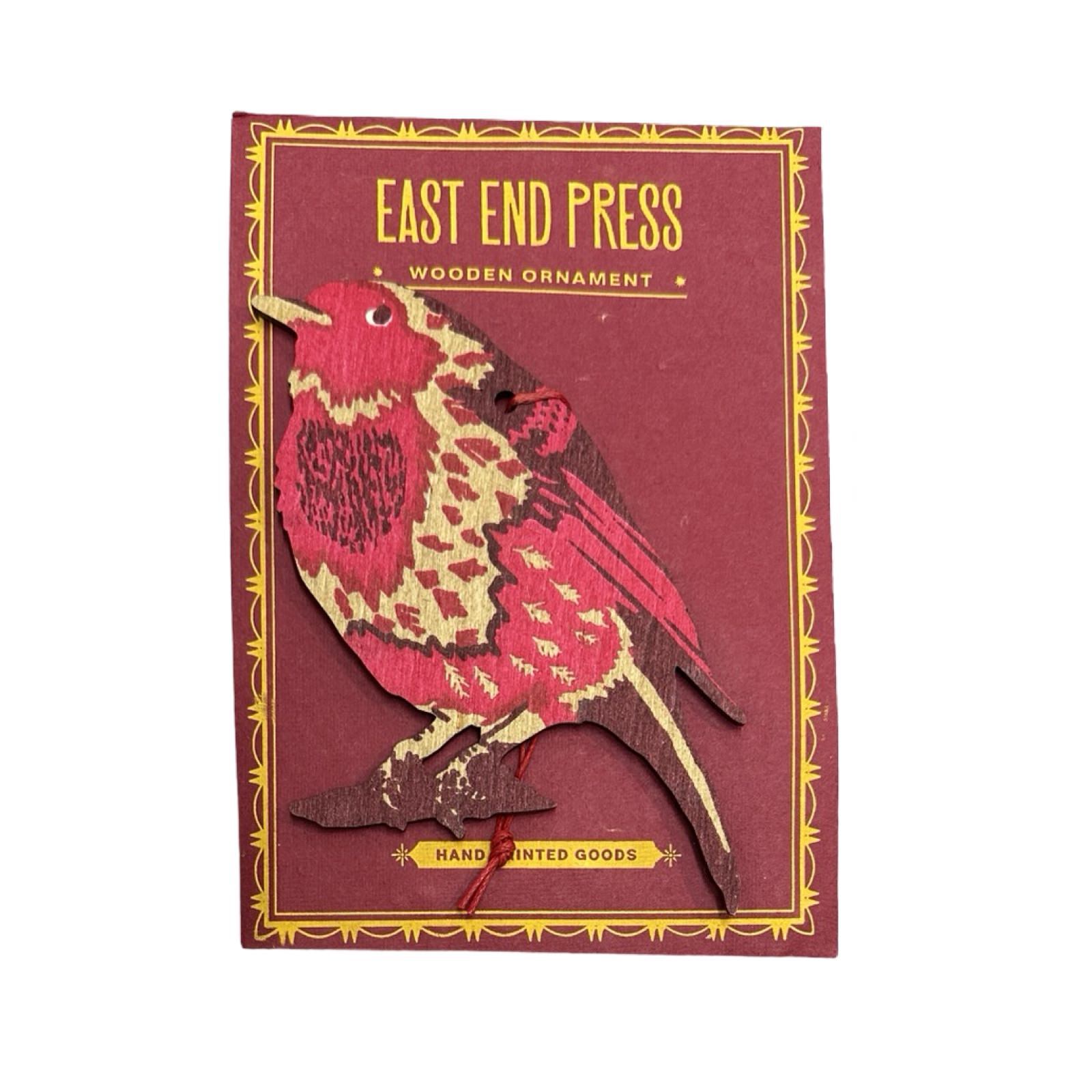 Hand-printed wooden robin Christmas decoration in red and gold against a red backing card.