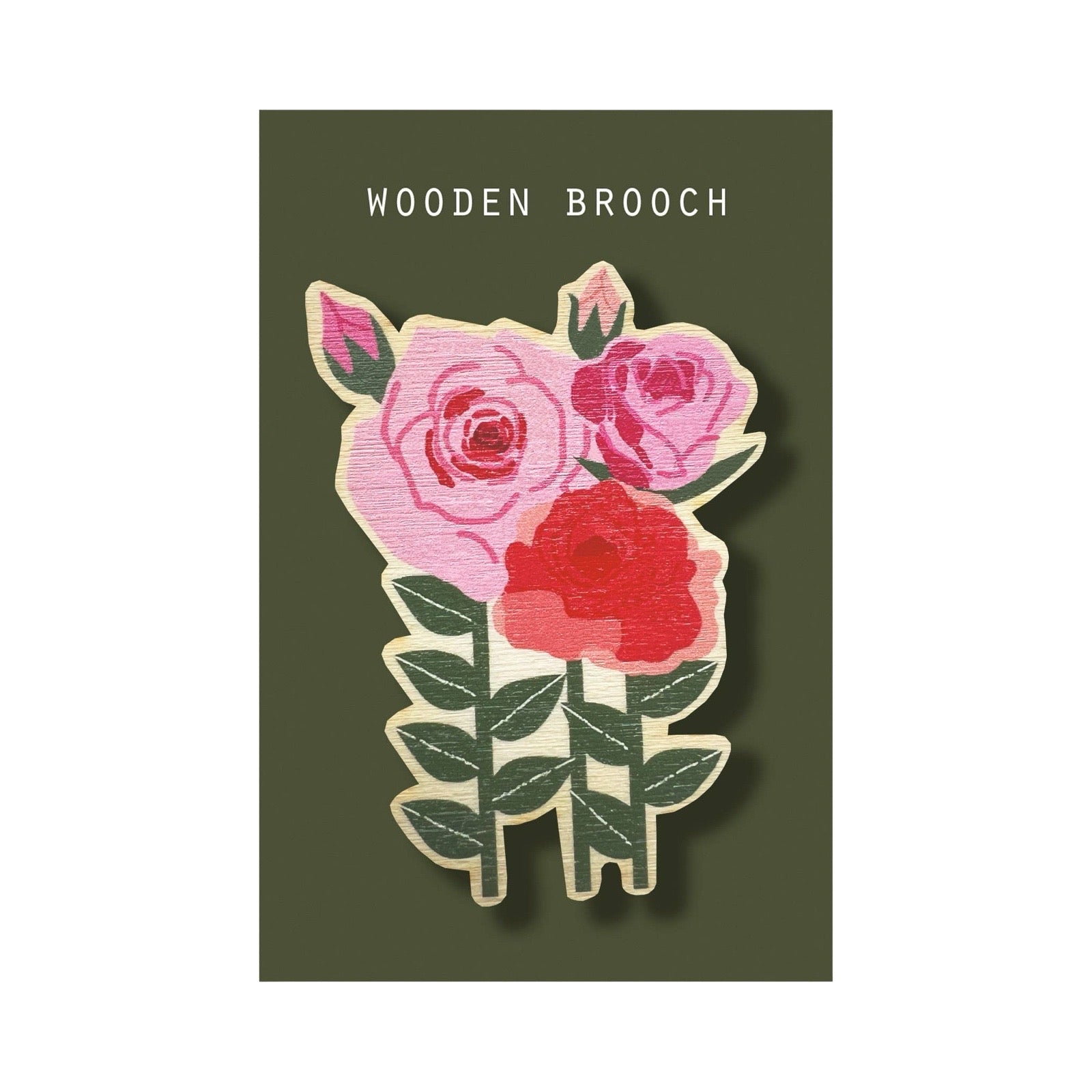 A floral wooden brooch featuring three roses in pink and red with green leaves, mounted on a dark olive green backing card that reads 'WOODEN BROOCH' at the top.