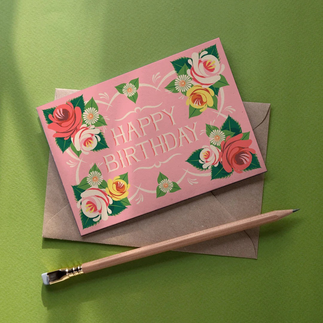 Pink birthday card with floral designs on a green background.