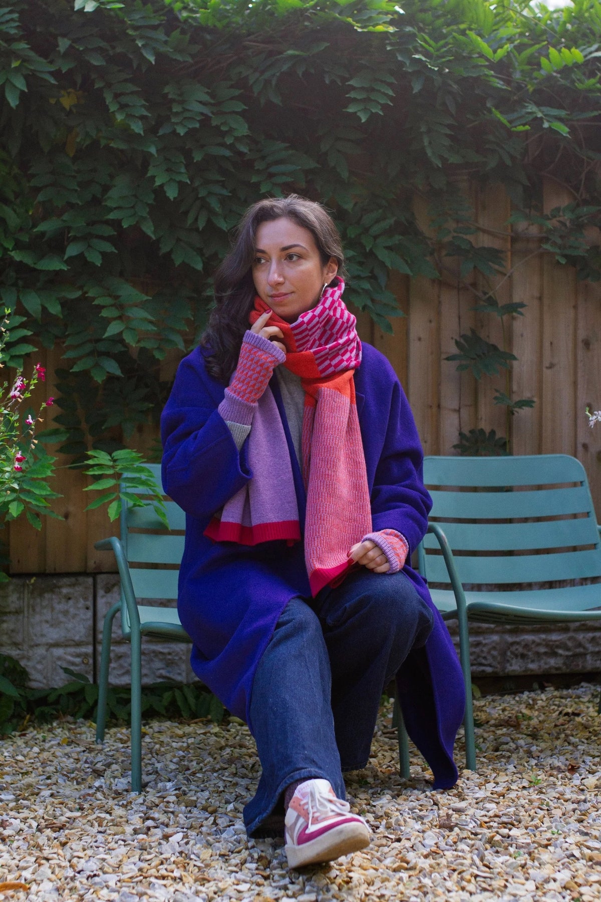 Woman sitting on a chair outdoors with a colourful scarf.