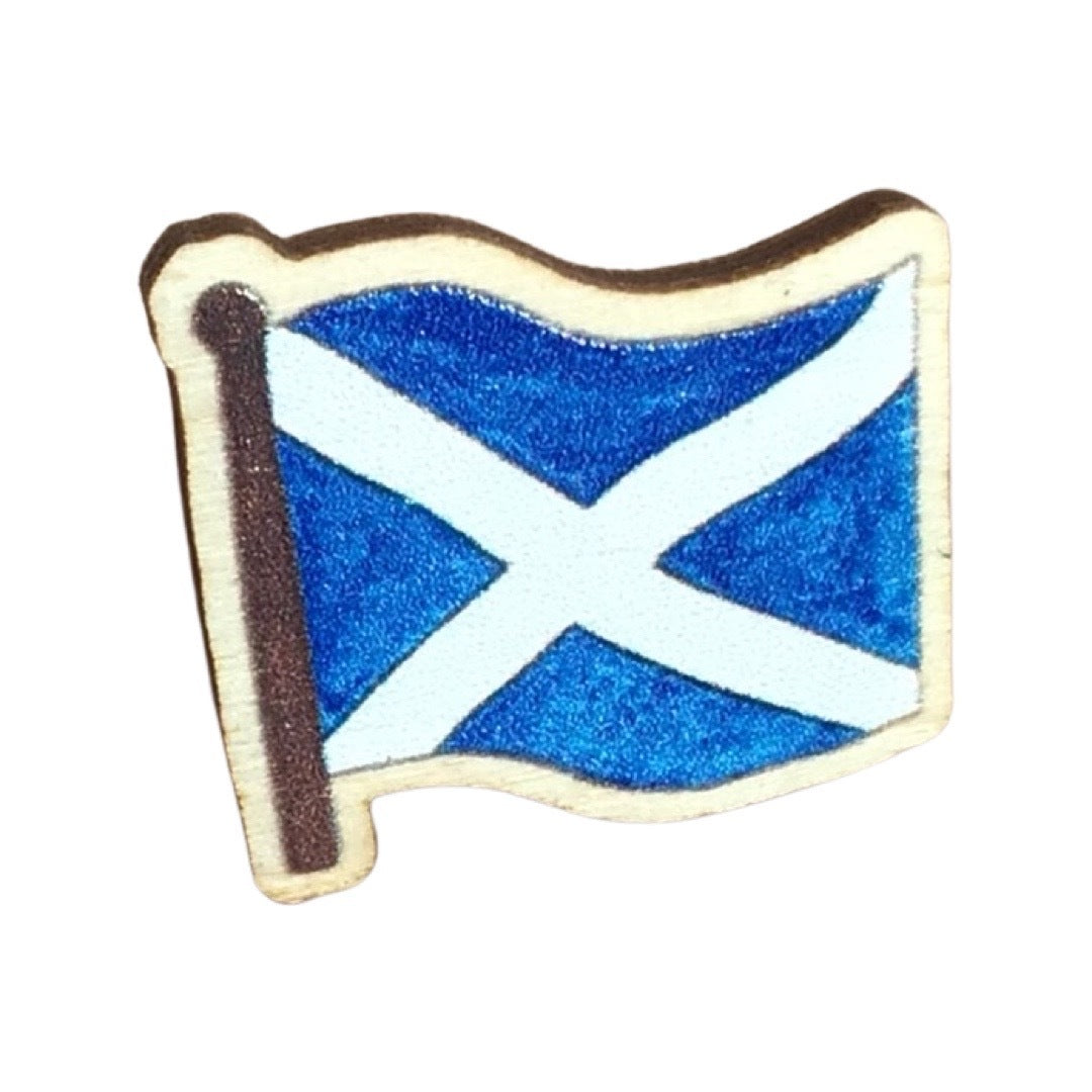 A mini wooden pin badge of the Scottish saltire flag.