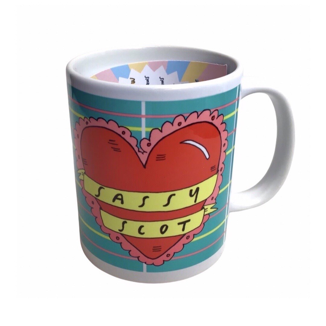 This mug features an illustration of a large red love heart on a blue tartan background and the text 'Sassy Scot' written inside a yellow banner.