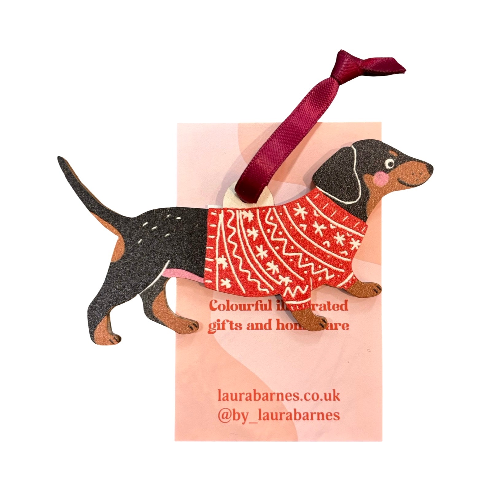 Decorative dog ornament with a red sweater on a pink card, featuring Laura Barnes branding.