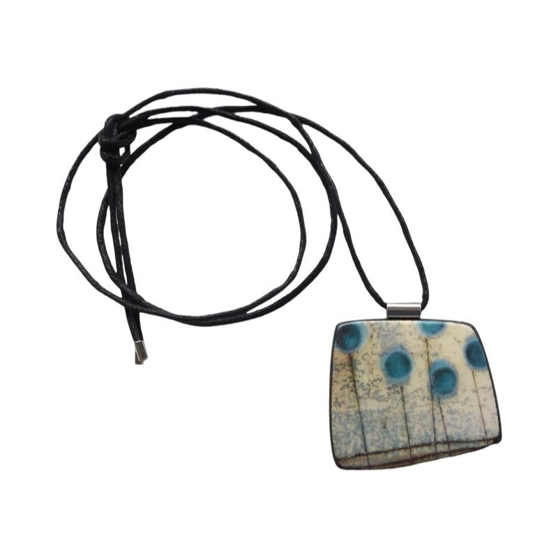 This pendent necklace is made from black porcelain casting slip layered with a white decorating slip and a ceramic decal.