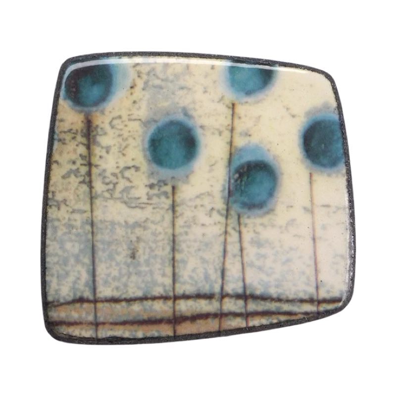 This porcelain brooch is made from black porcelain casting slip layered with a white decorating slip and a ceramic decal.