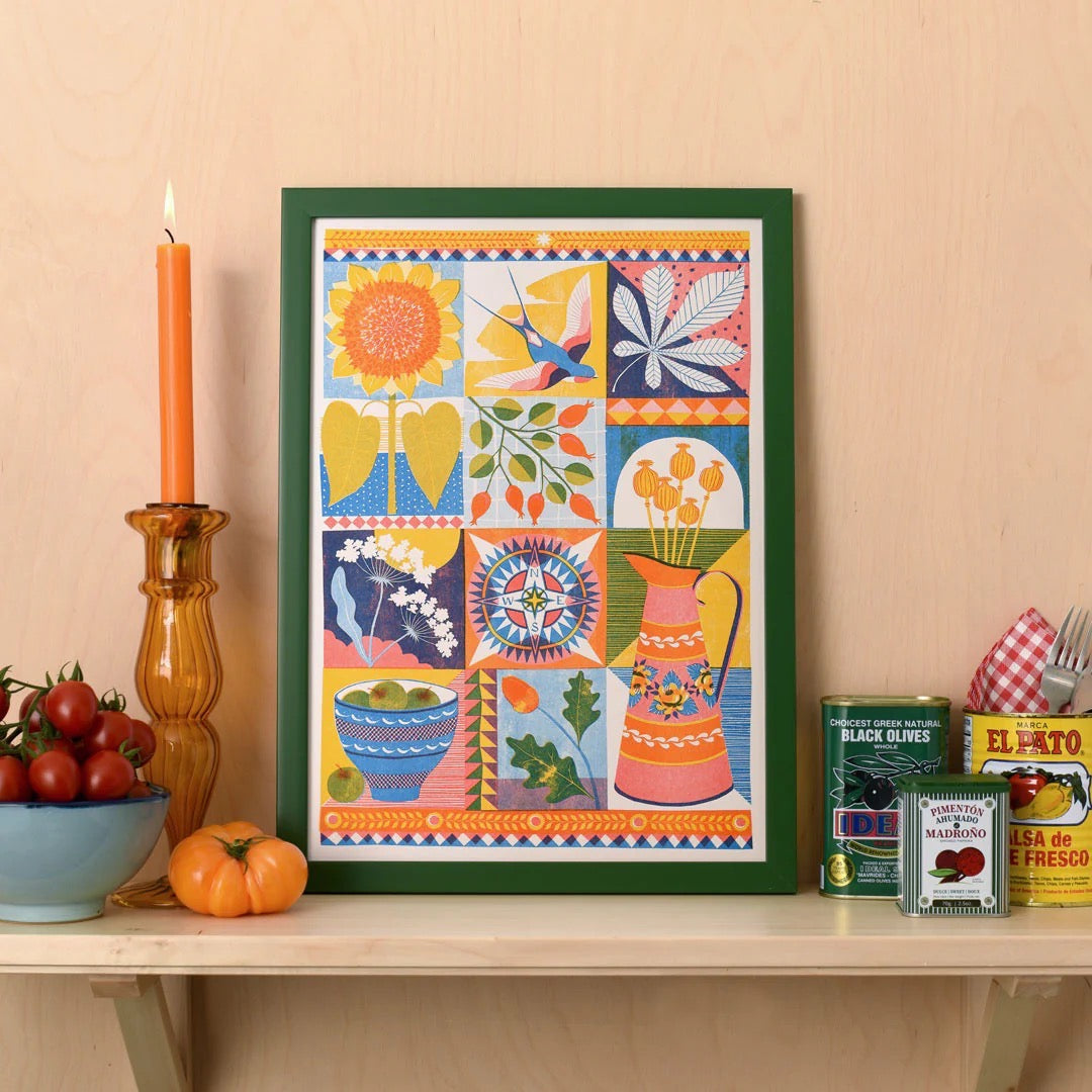 Framed colourful artwork on a table with kitchen items.