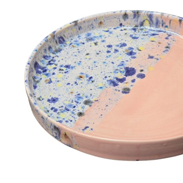 Handmade ceramic trays with half in a shoreline design and half block colour, in pink and blue.