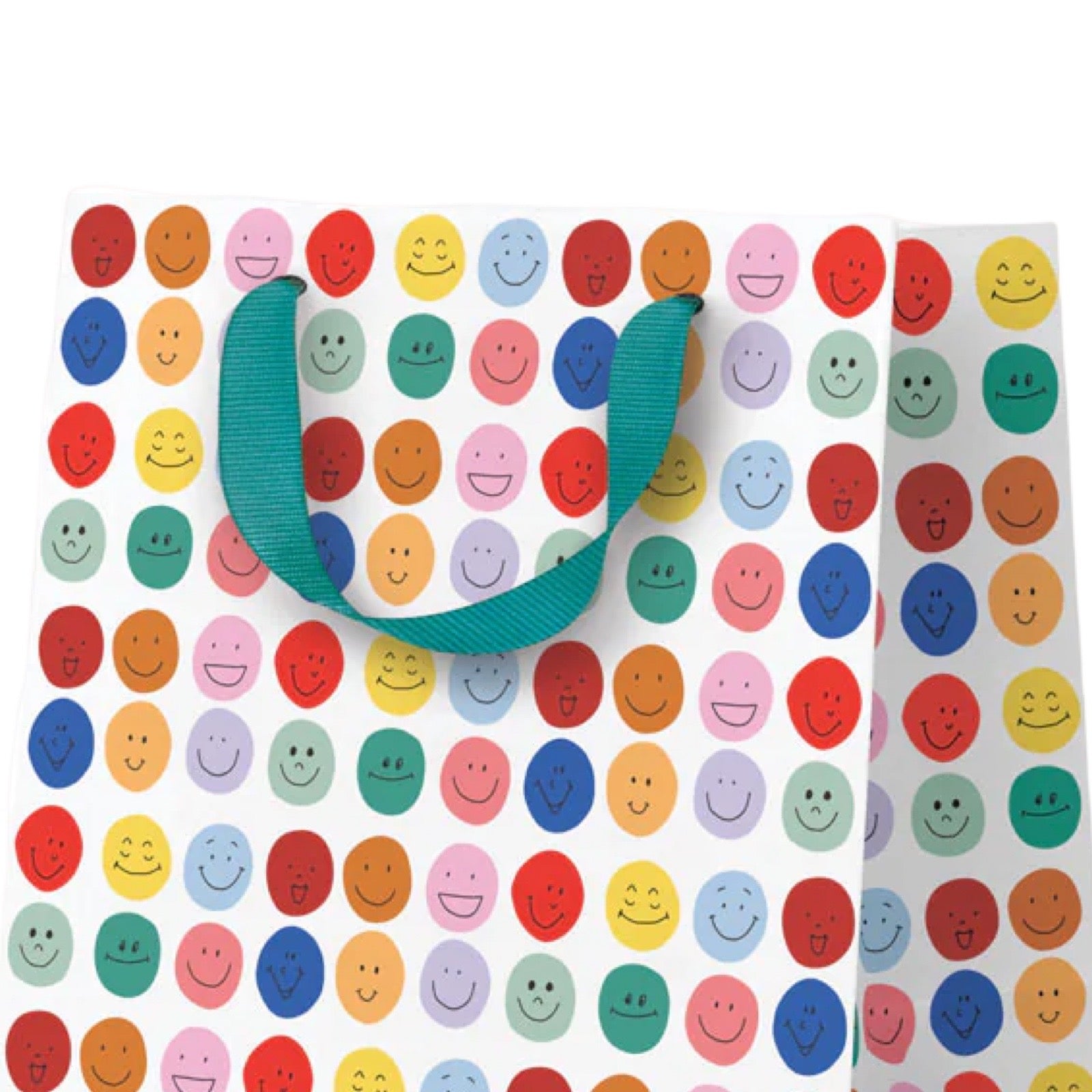 A white gift bag covered in a colourful smiley face pattern, with teal ribbon handles, shown on a white background.