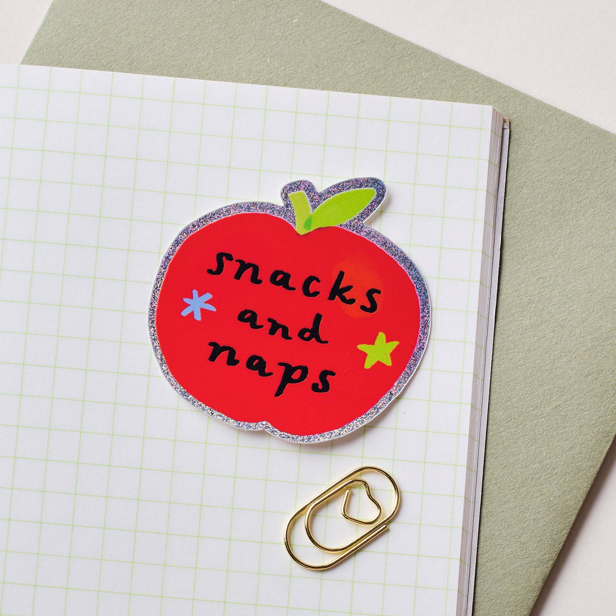 Red apple-shaped sticker with 'snacks and naps' text on a notebook page.