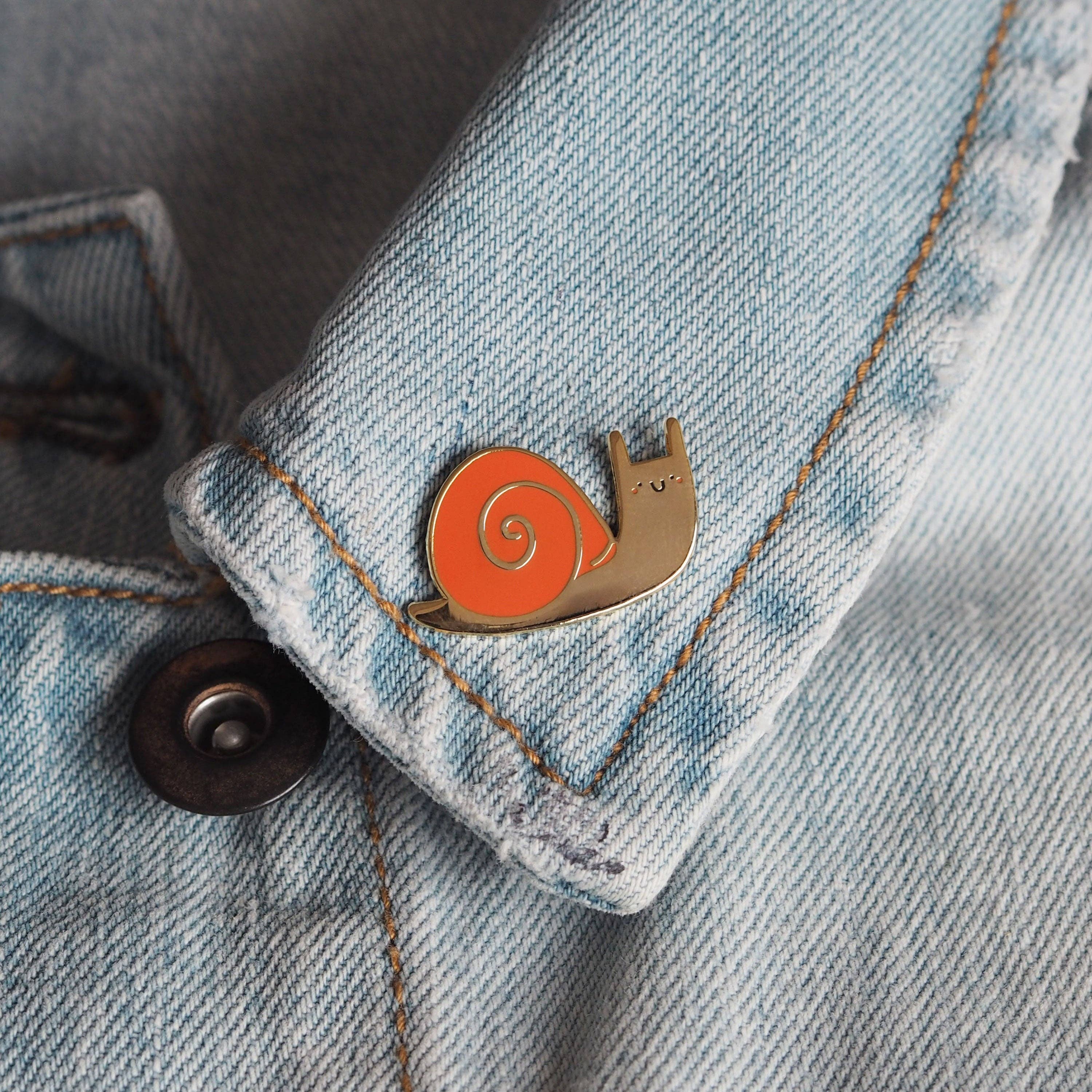 Snail-shaped pin on a denim jacket.