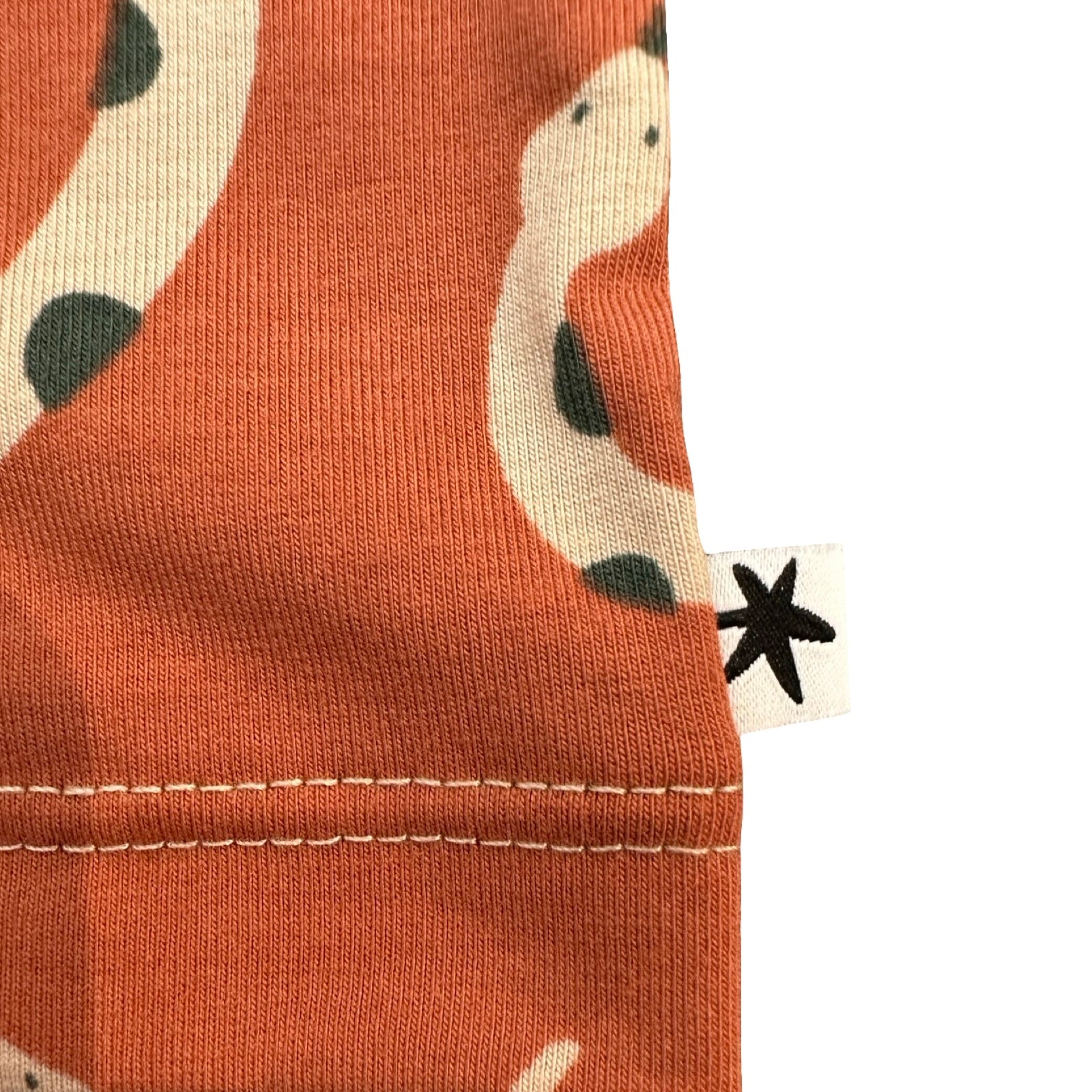Close-up of a orange fabric with a pattern and a visible brand tag.