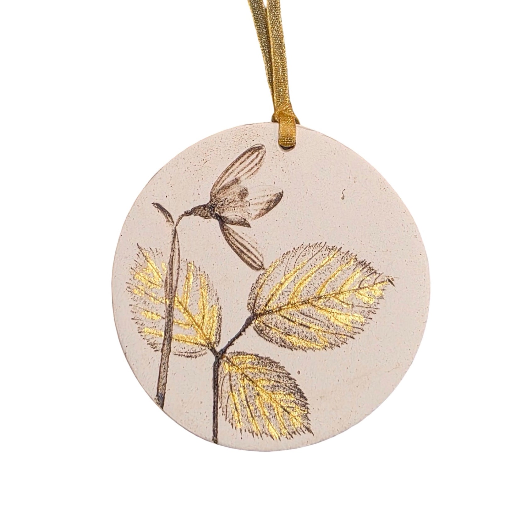 Round ceramic ornament with gold leaf design on a white background