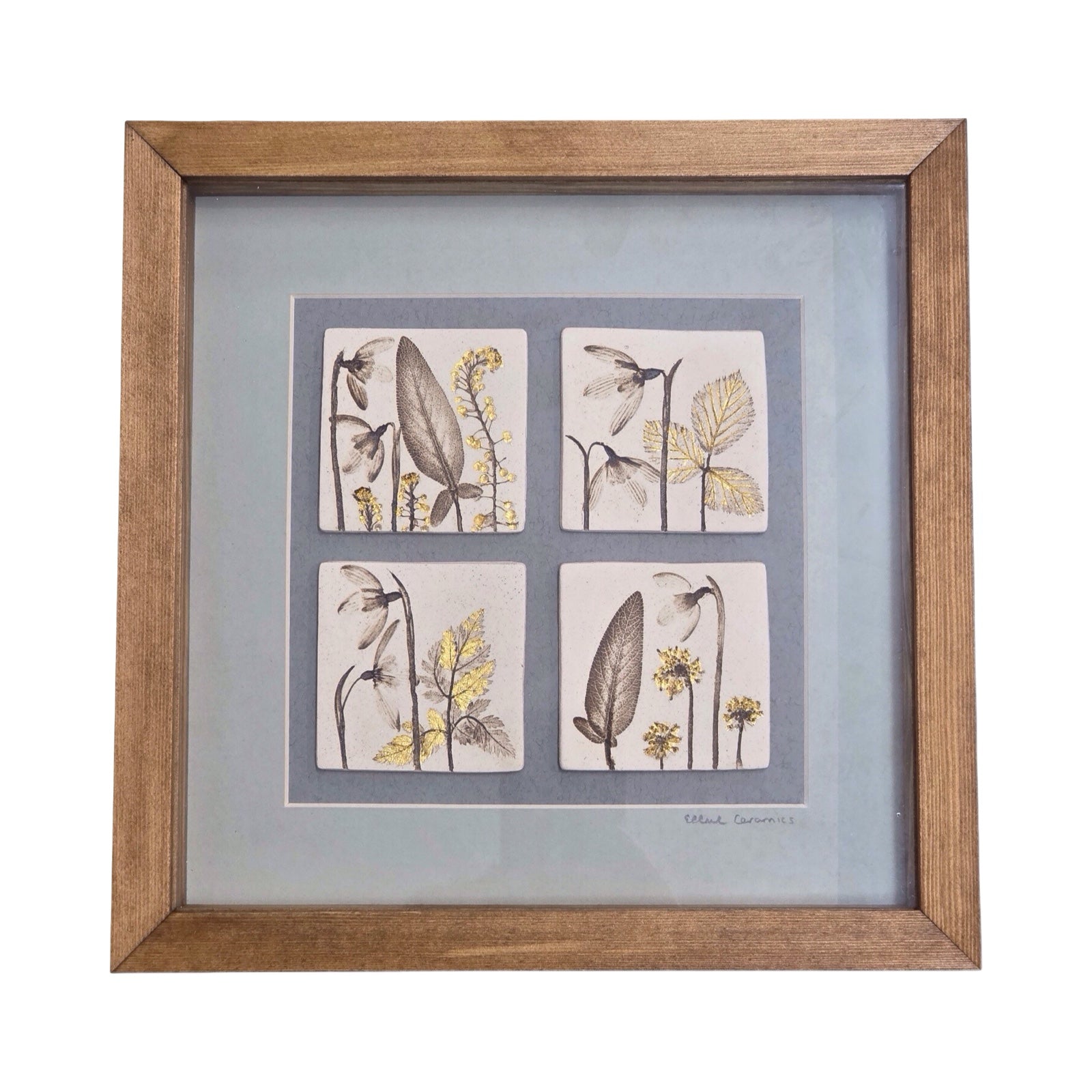 Framed artwork with four botanical tiles featuring snowdrops on a light grey background in an oak frame. 