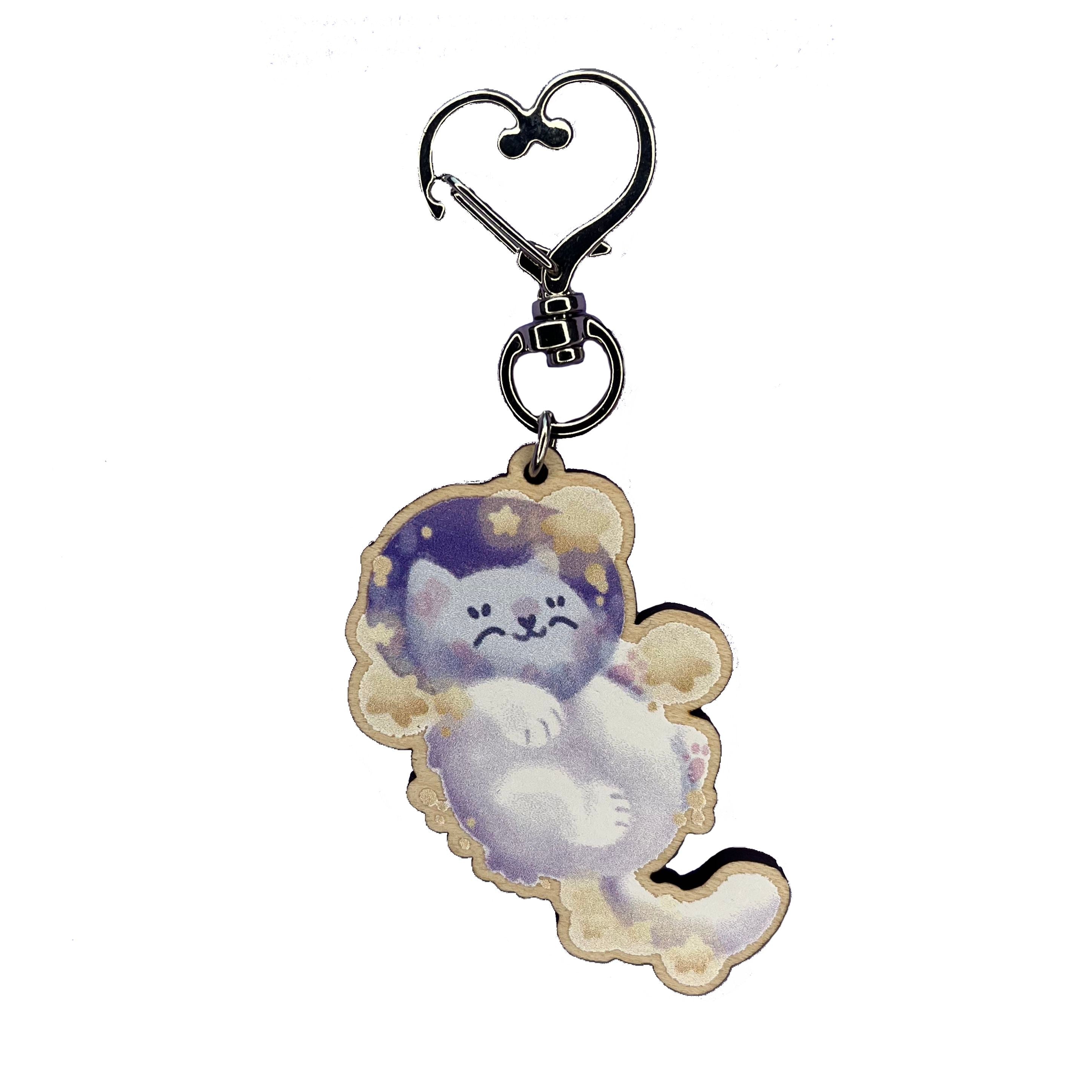 Astronaut cat snoozing amongst yellow stars in a keyring design.