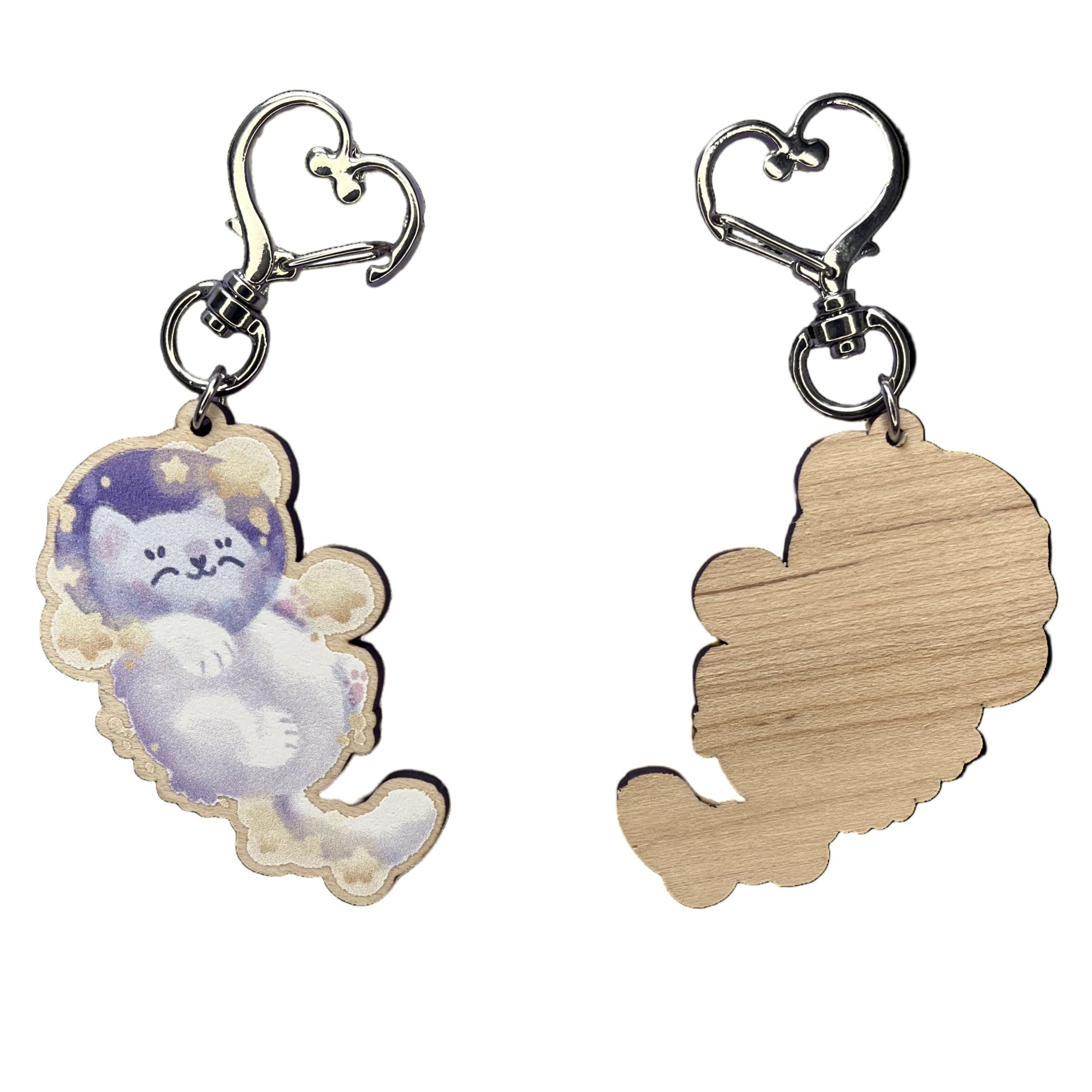 Astronaut cat snoozing amongst yellow stars in a keyring design - front (left), back (right)