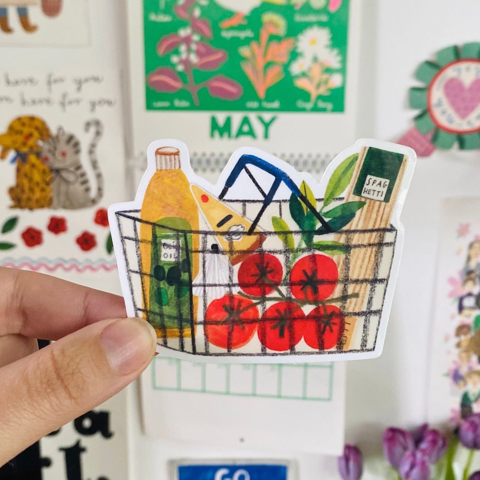 Sticker of a shopping basket with groceries held by a hand, with a colourful background.