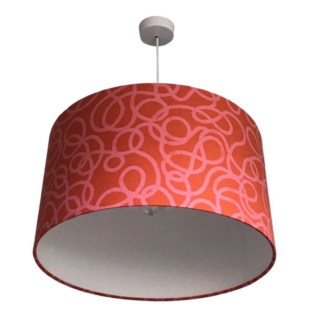 Drum lampshade covered in red canvas fabric with pink squiggles