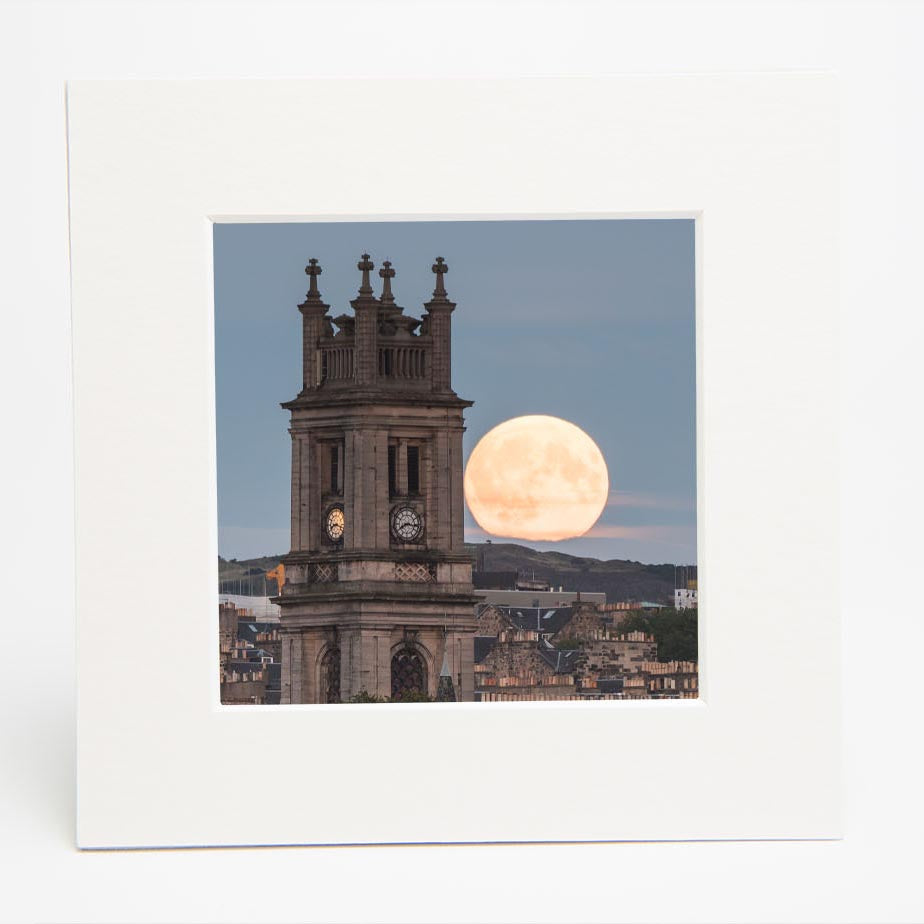 An image of St Stephen's Church with a large moon in the sky in a square mounted print. 