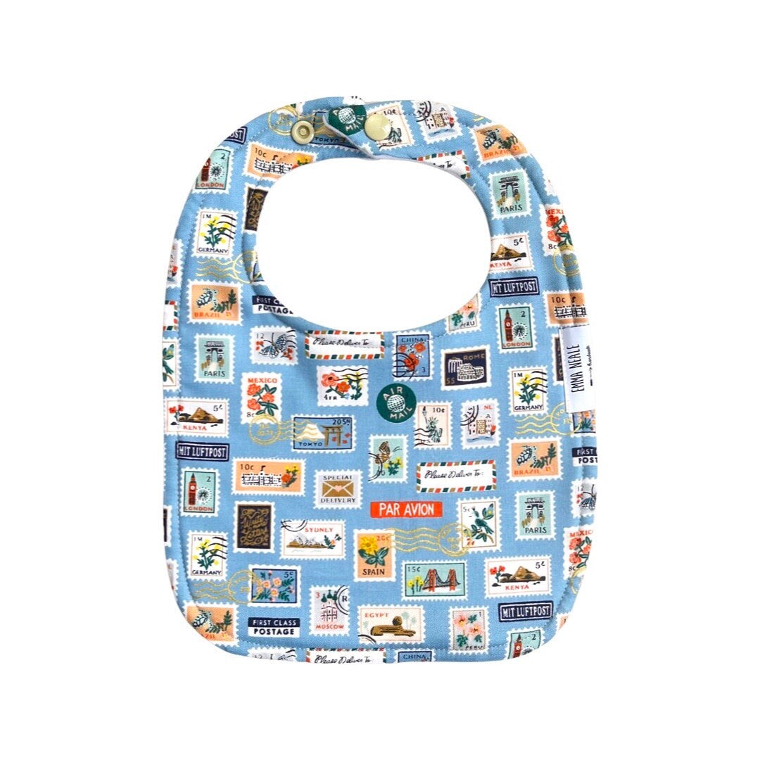 A blue and white baby bib with a traditional style and a pattern of stamps and envelopes.