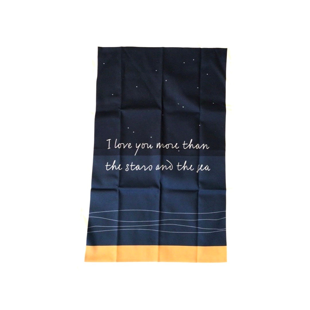 Tea towel featuring a starry night sky above the sea and the text 'I Love You More than the Stars and the Sea'. 