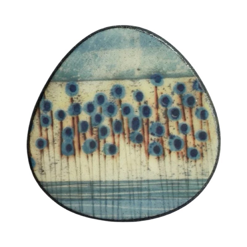 This porcelain oval brooch is made from black porcelain casting slip layered with a white decorating slip and a ceramic decal.