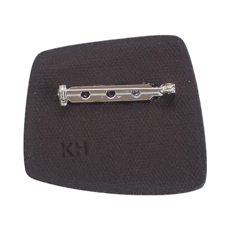 This porcelain brooch is made from black porcelain casting slip layered with a white decorating slip and a ceramic decal.
