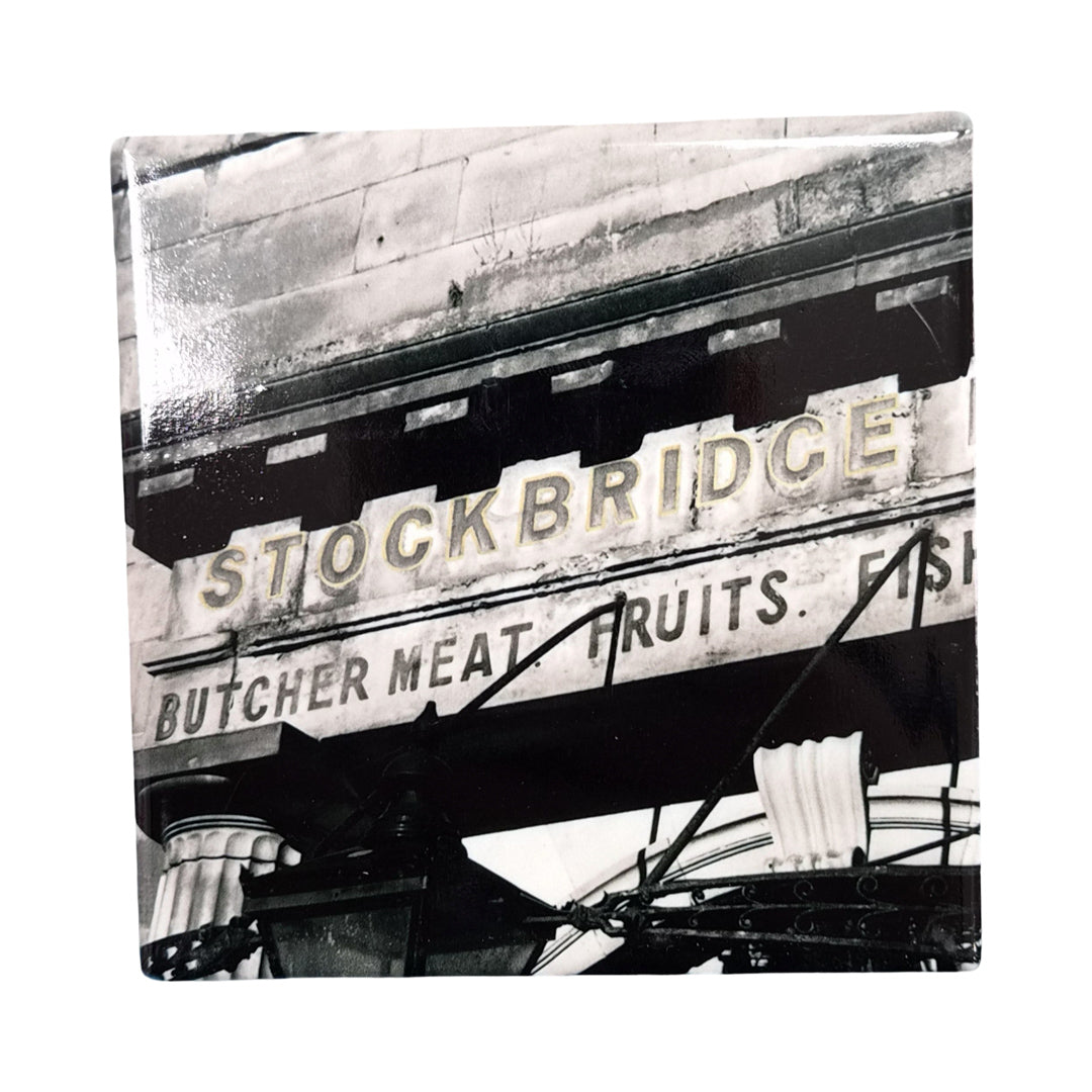 Black and white sign for Stockbridge market on a ceramic coaster. 