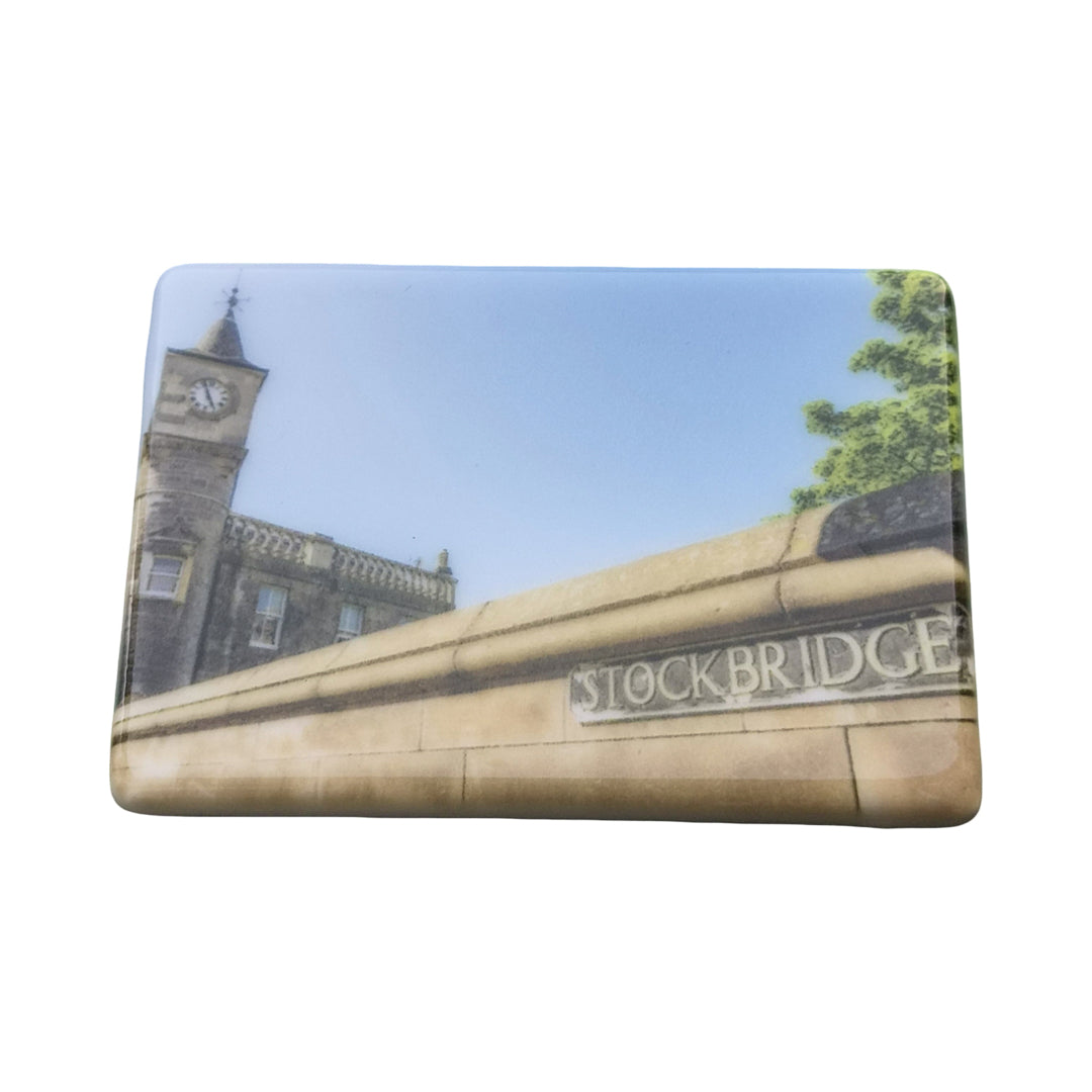 A rectangular plaque or sign featuring a printed photograph of Stockbridge.