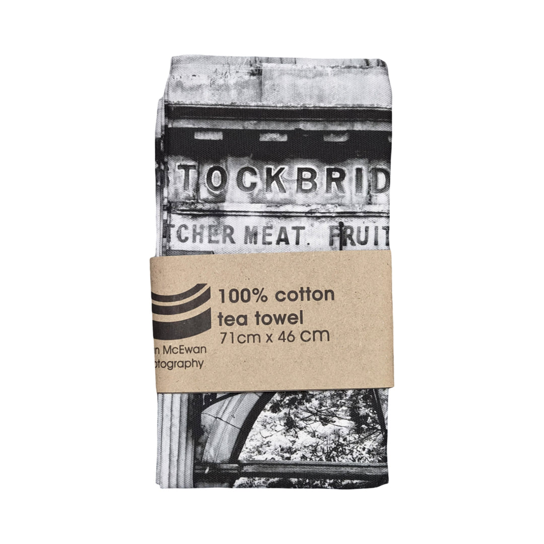 Tea towel with black and white design and cardboard packaging on a white background