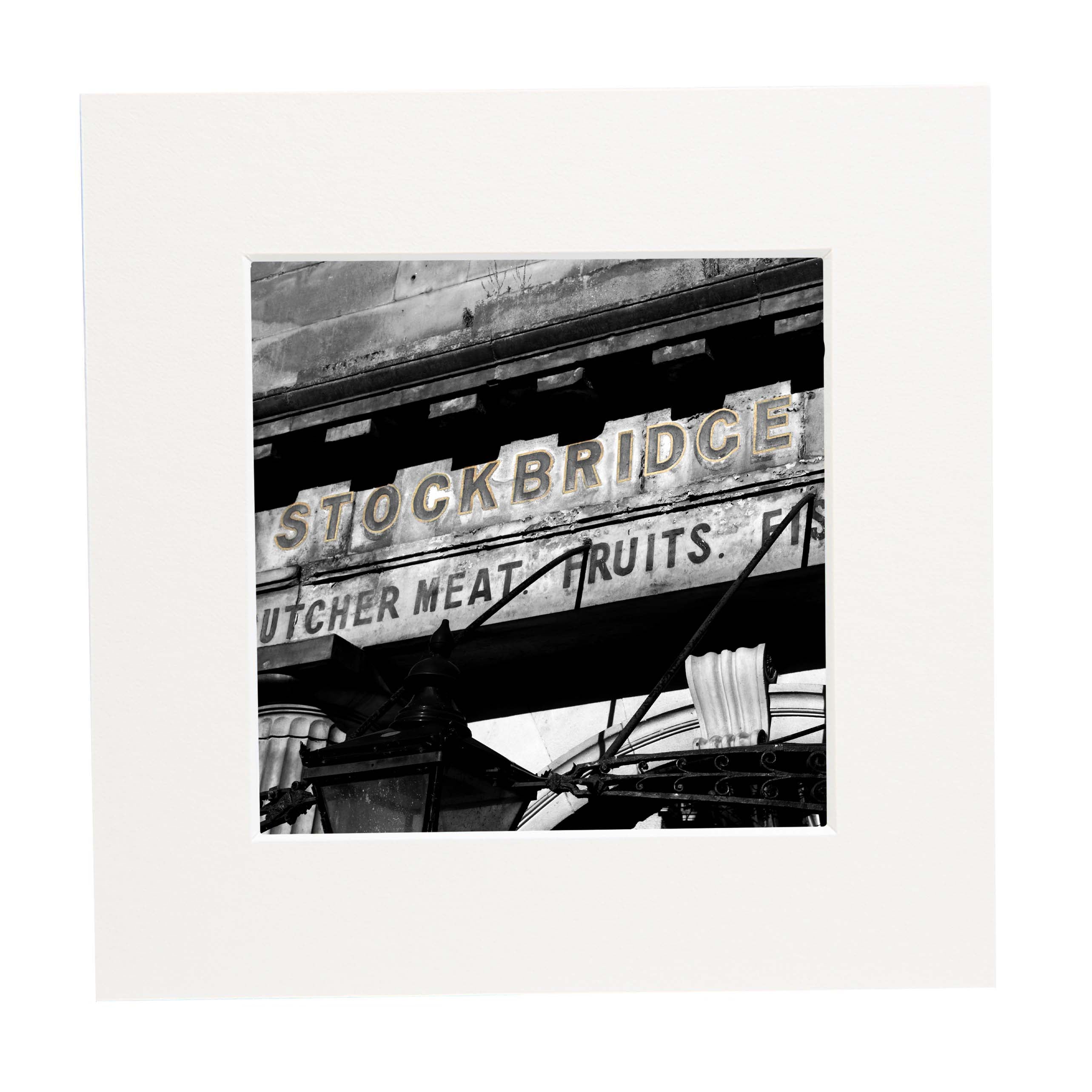 Black and white photograph of an old sign with 'Stockbridge' and 'Butcher Meat Fruits' text.