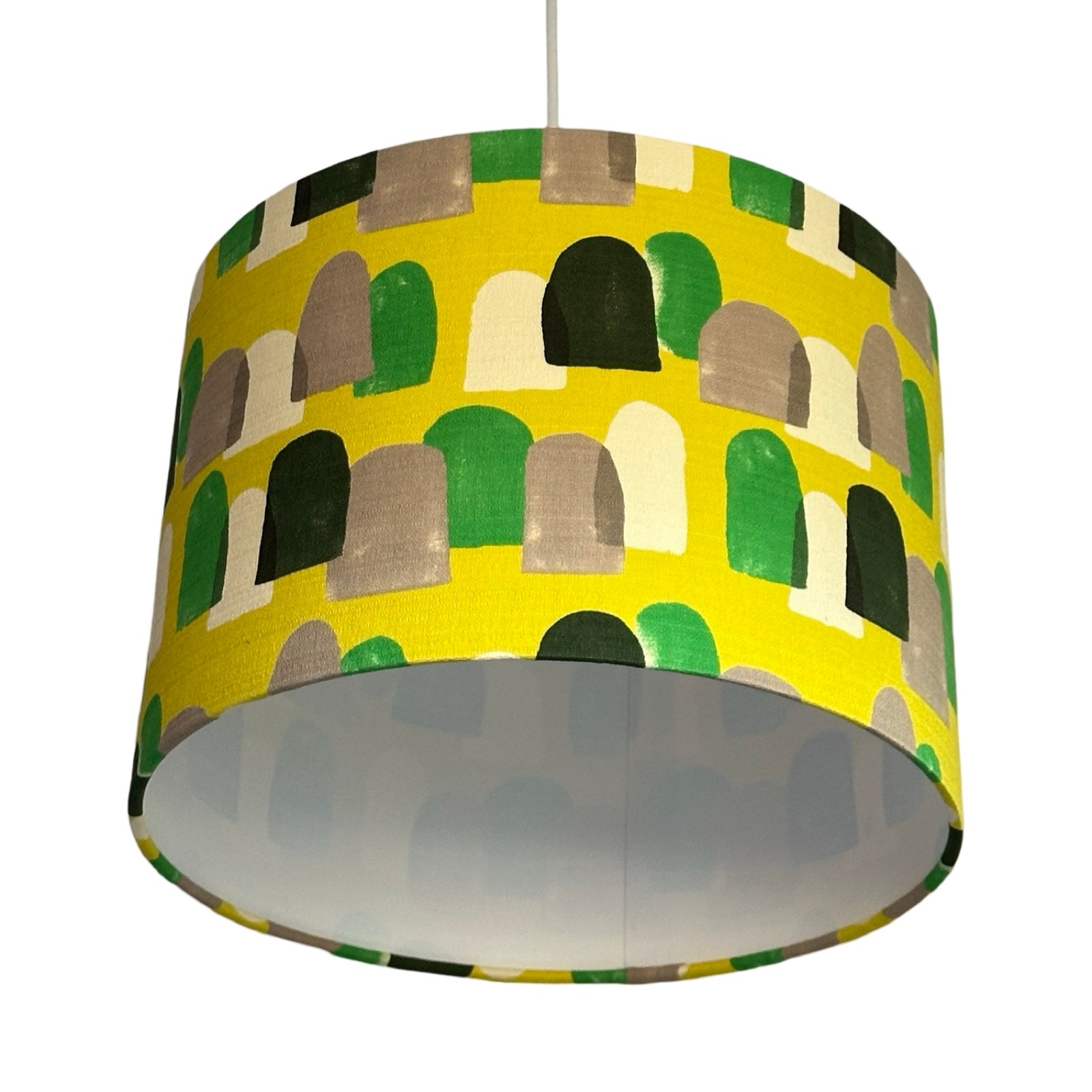 Drum lampshade covered in barkcloth fabric in yellow with green, navy, white and brown stones.