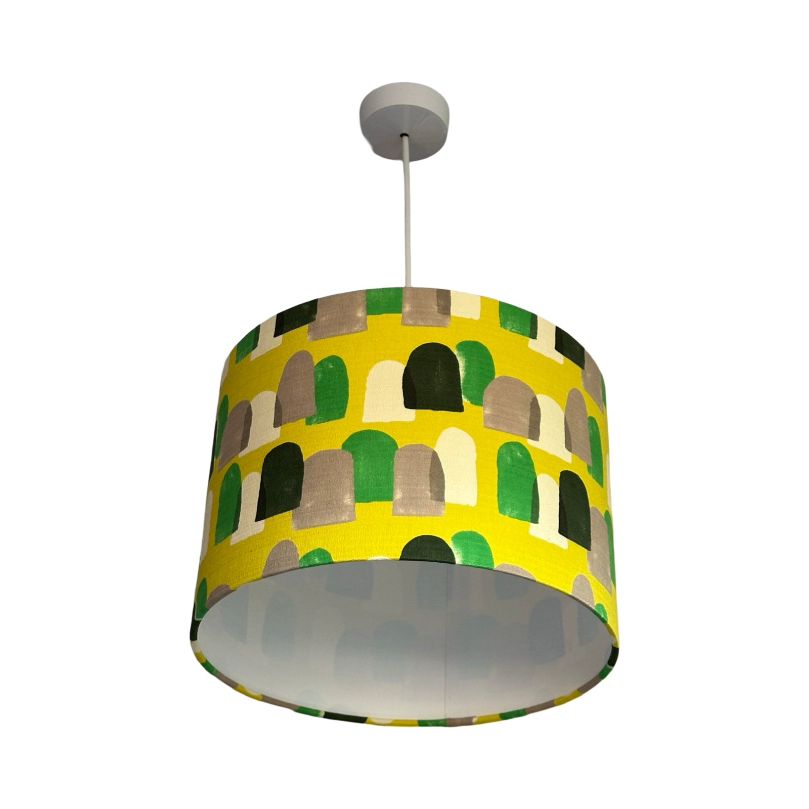 Drum lampshade covered in barkcloth fabric in yellow with green, navy, white and brown stones.