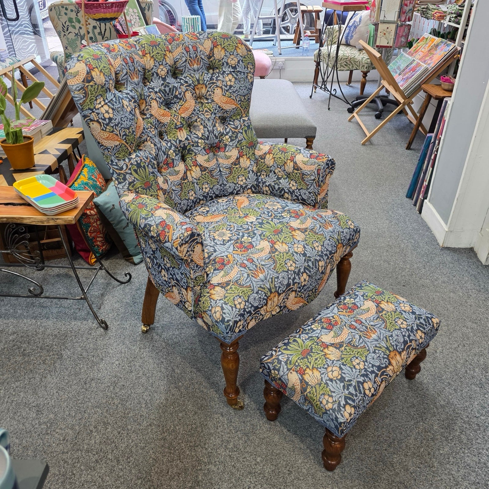 Floral-patterned armchair and footstool in a room with furniture and decor items.